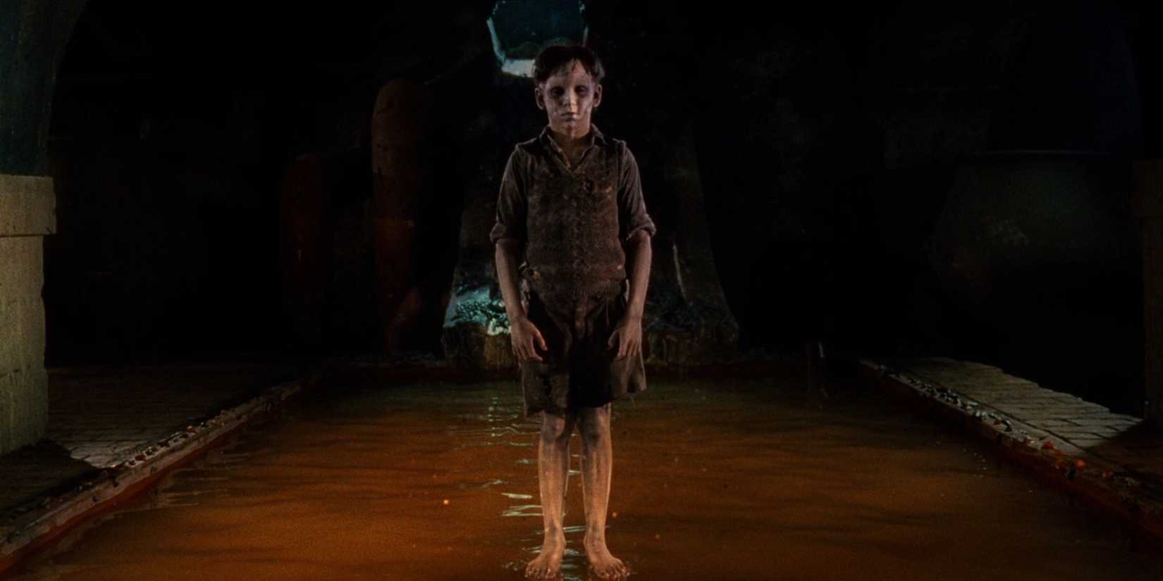 A creepy boy standing in the middle of a sewer in 'The Devil's Backbone'