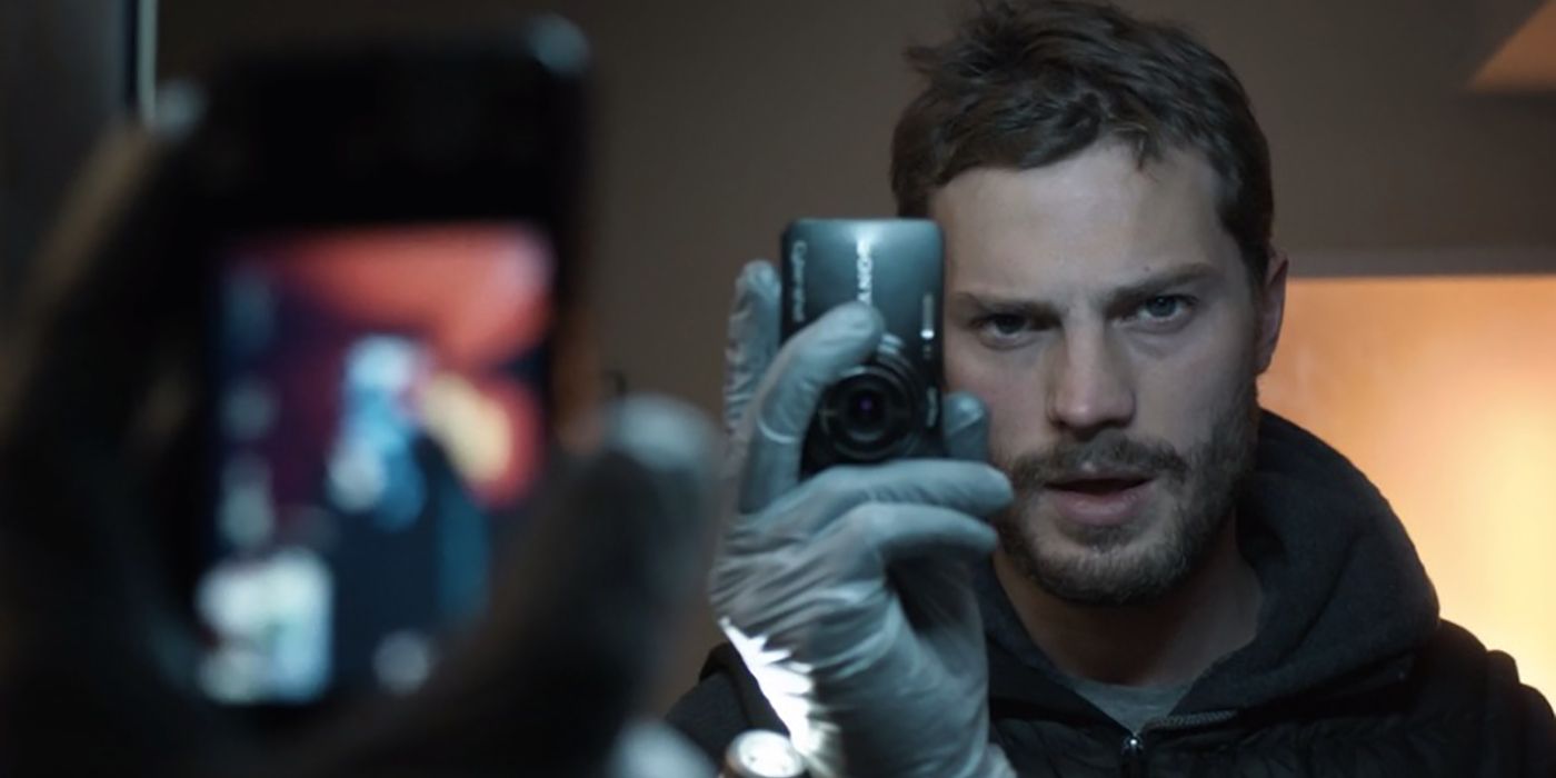 Paul Spector de The Fall tenant une petite caméra devant un miroir.