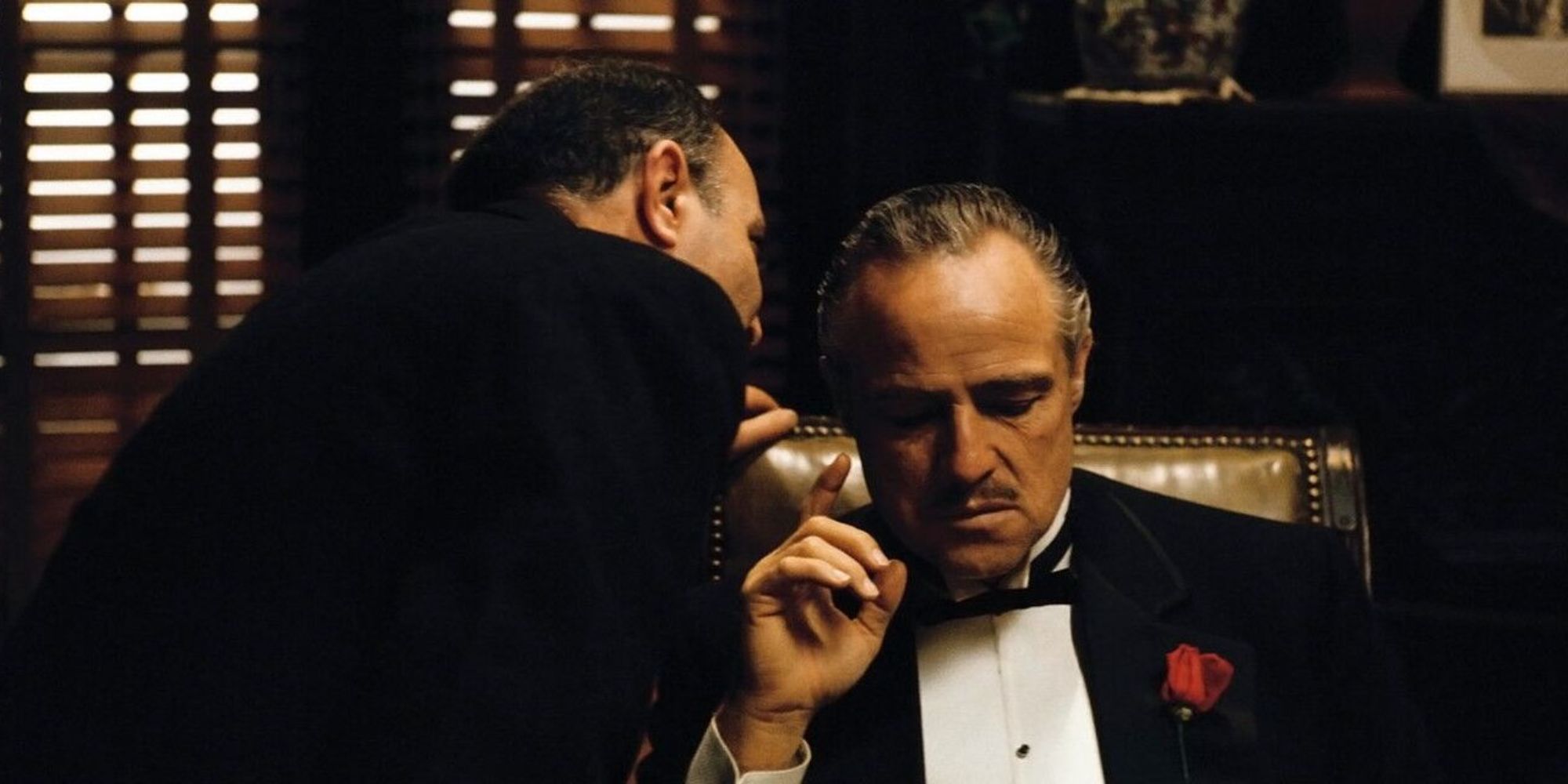 Un homme chuchotant à l'oreille de Marlon Brando dans Le Parrain (1972) (1)