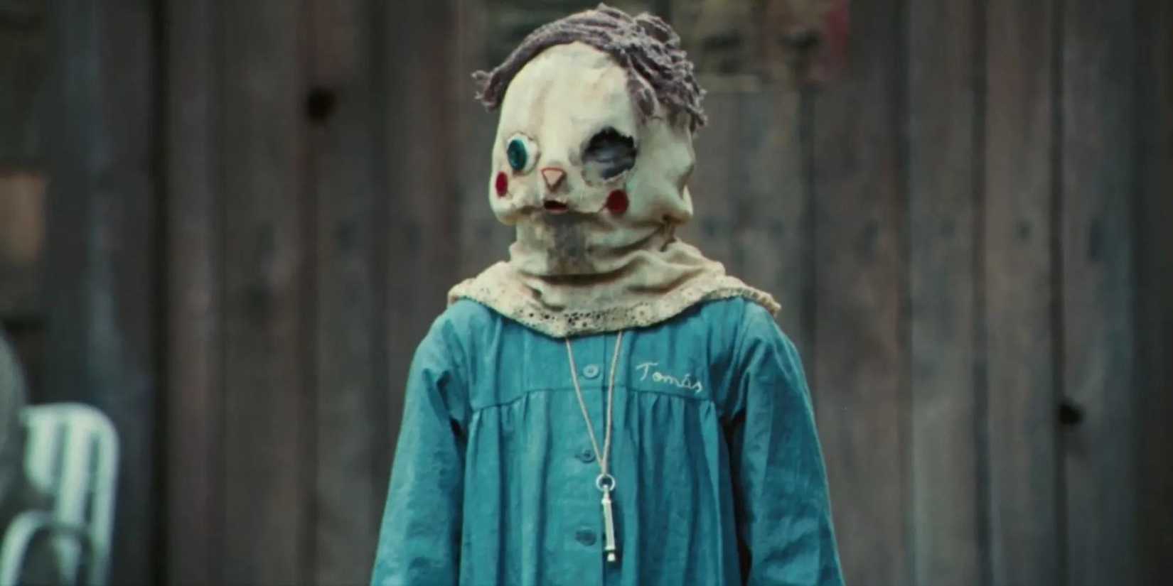 Oscar Casas as Tomás wearing a mask and a blue uniform in The Orphanage.
