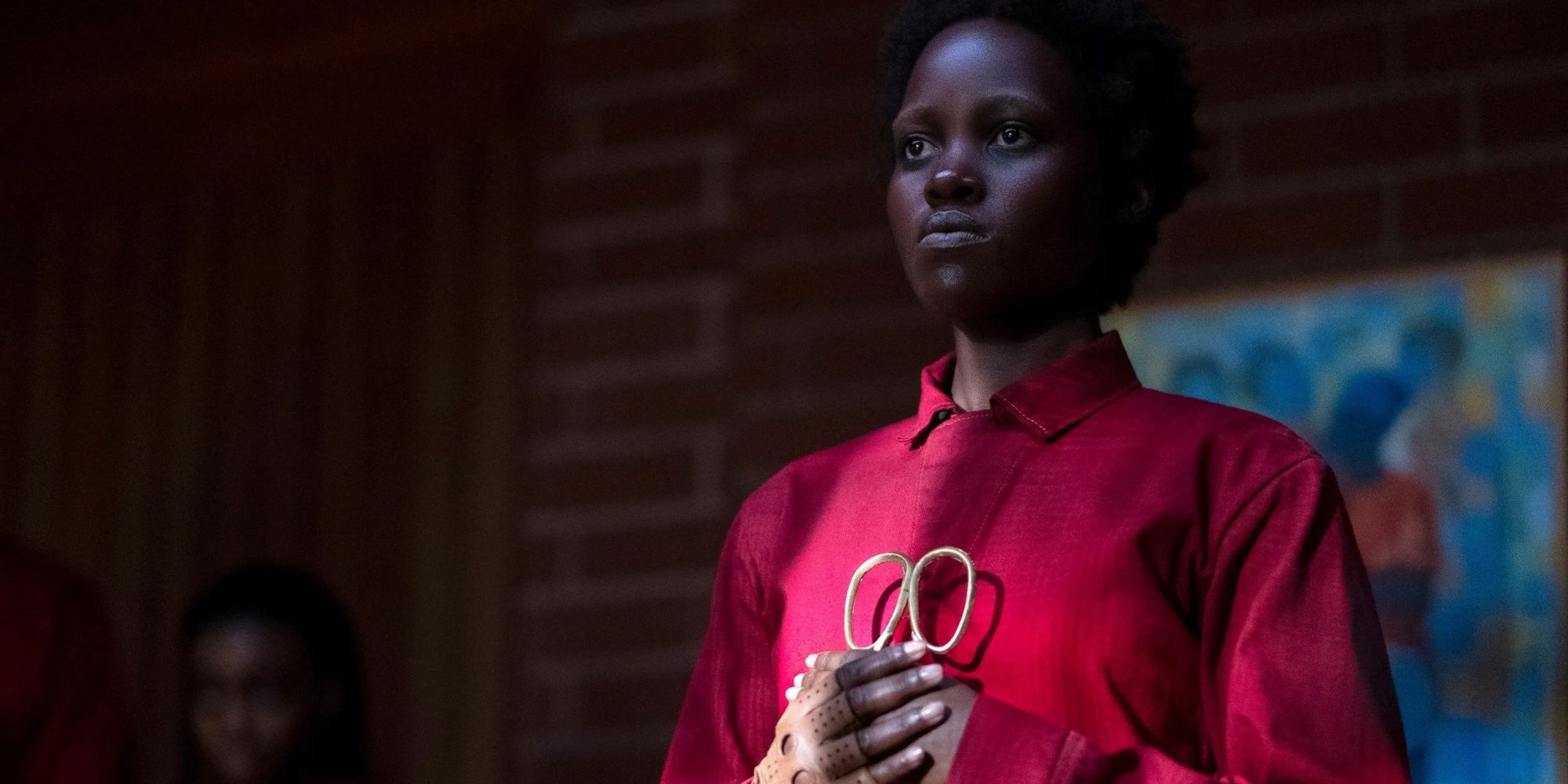 A still from 'Us', with a woman in a red jumpsuit holding scissors to her chest