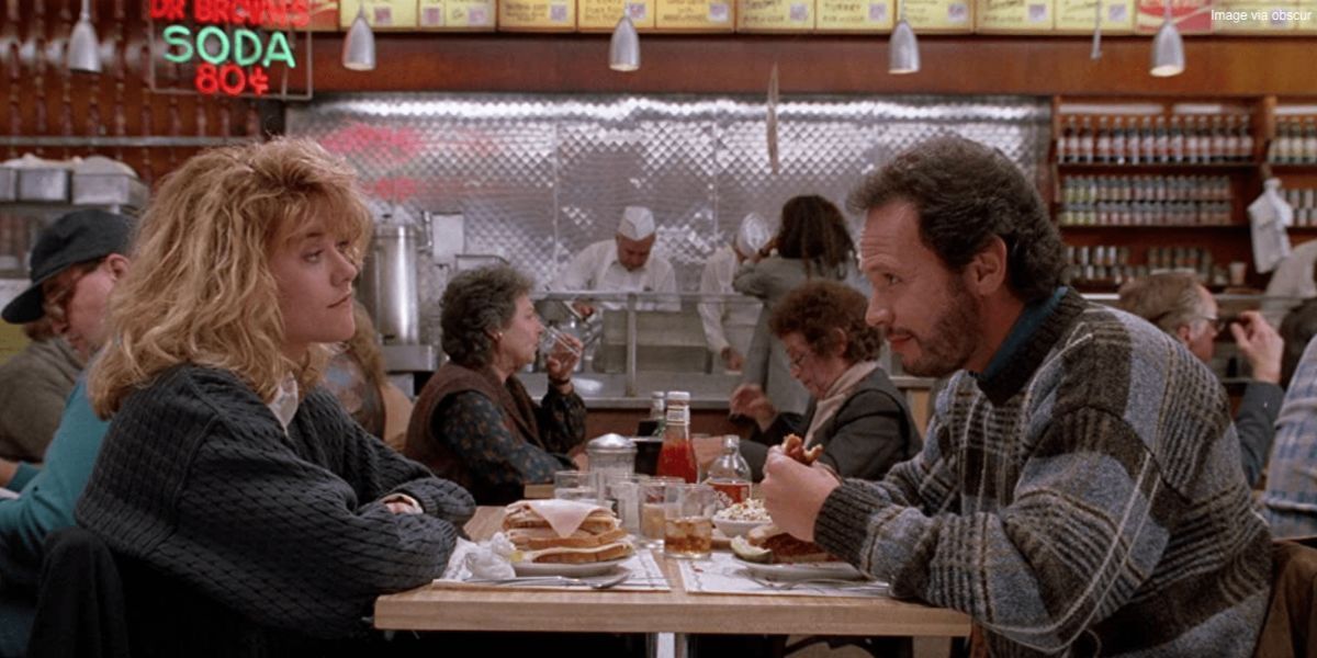 Meg Ryan and Billy Crystal sitting across from each other at a table in When Harry Met Sally