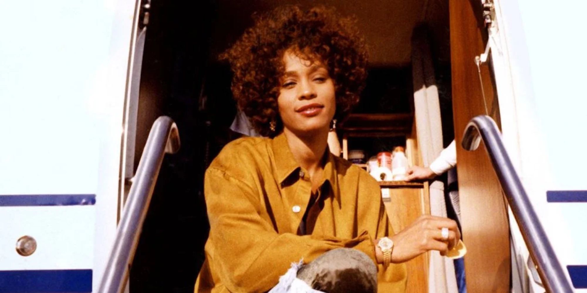 Whitney Houston sitting and smiling in 'Whitney'