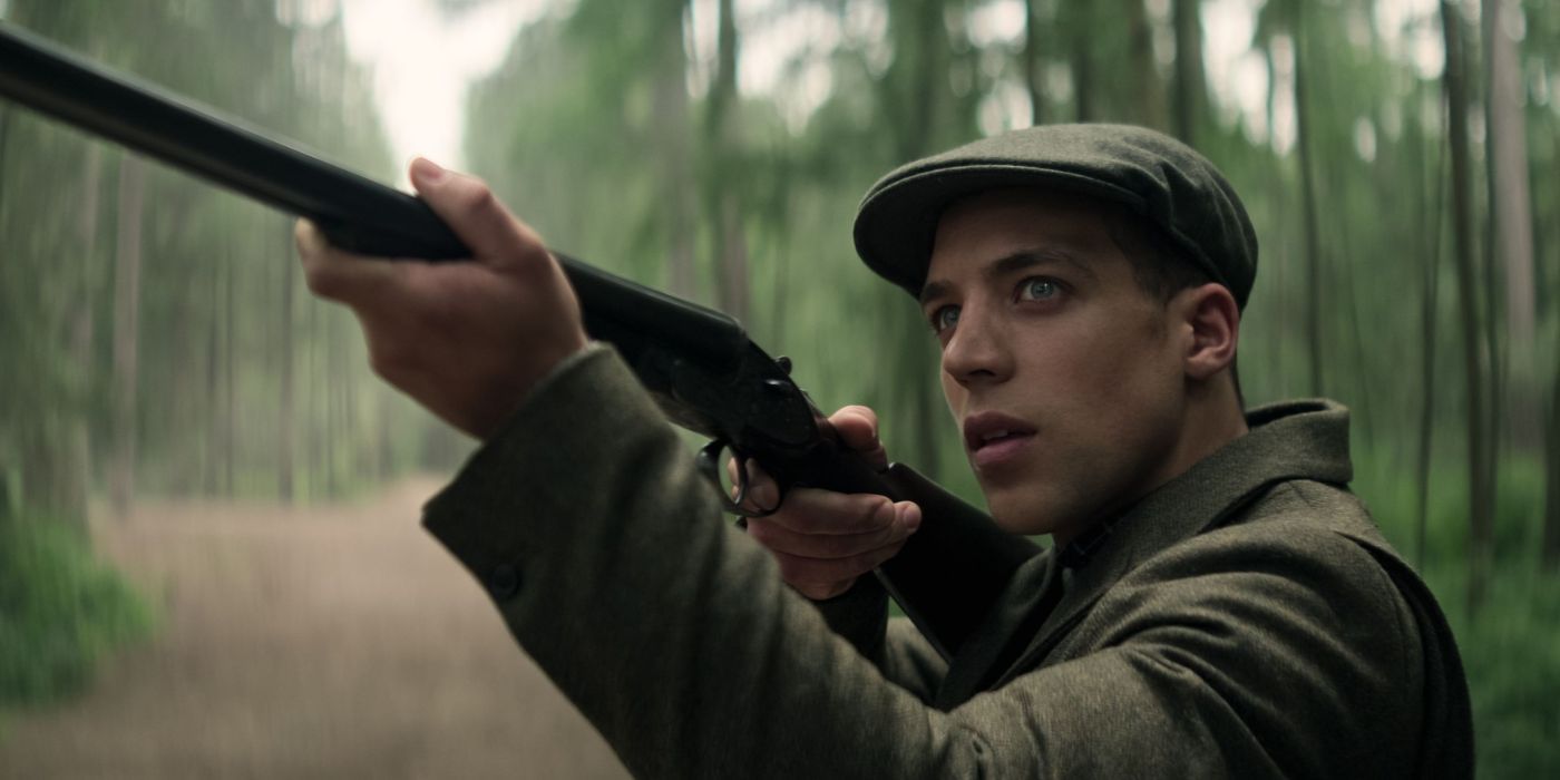 Ben Wiggins dans le rôle de Roald tenant un fusil de chasse dans les bois dans la saison 4 de 'You'.
