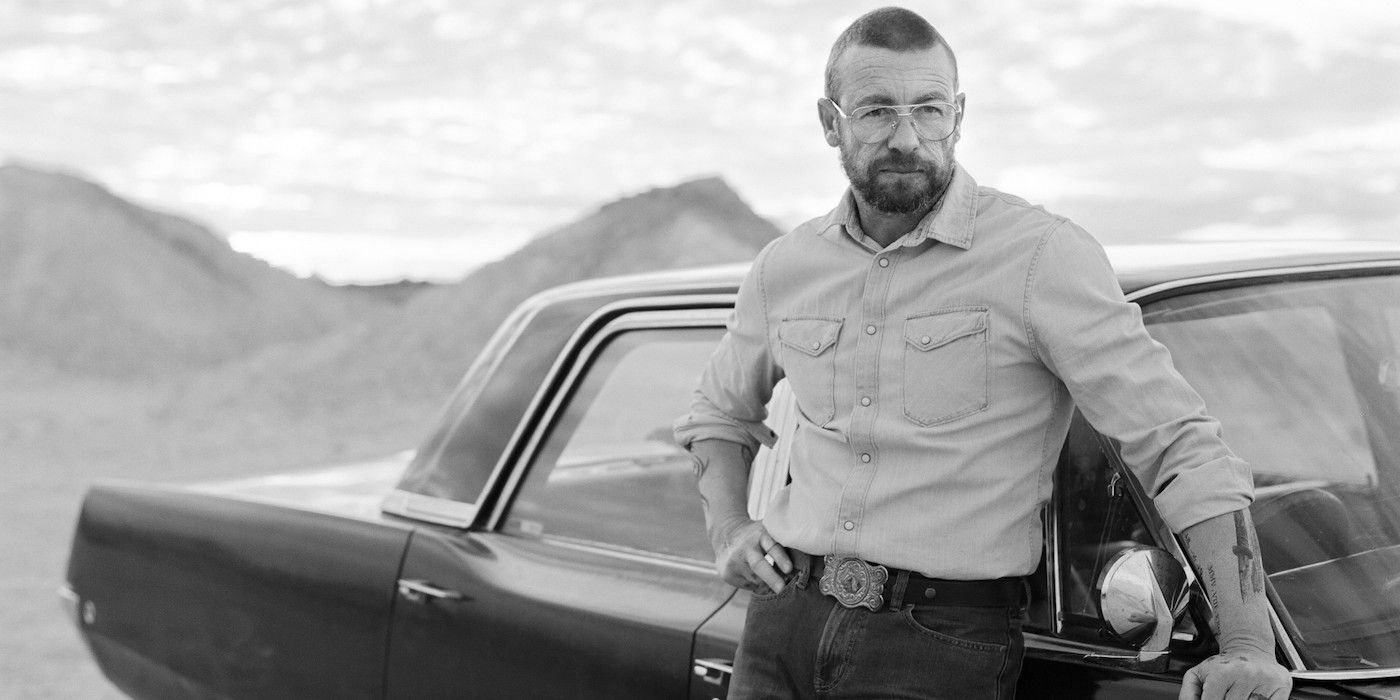 Simon Baker as Travis Hurley standing in front of a car in Limbo. 