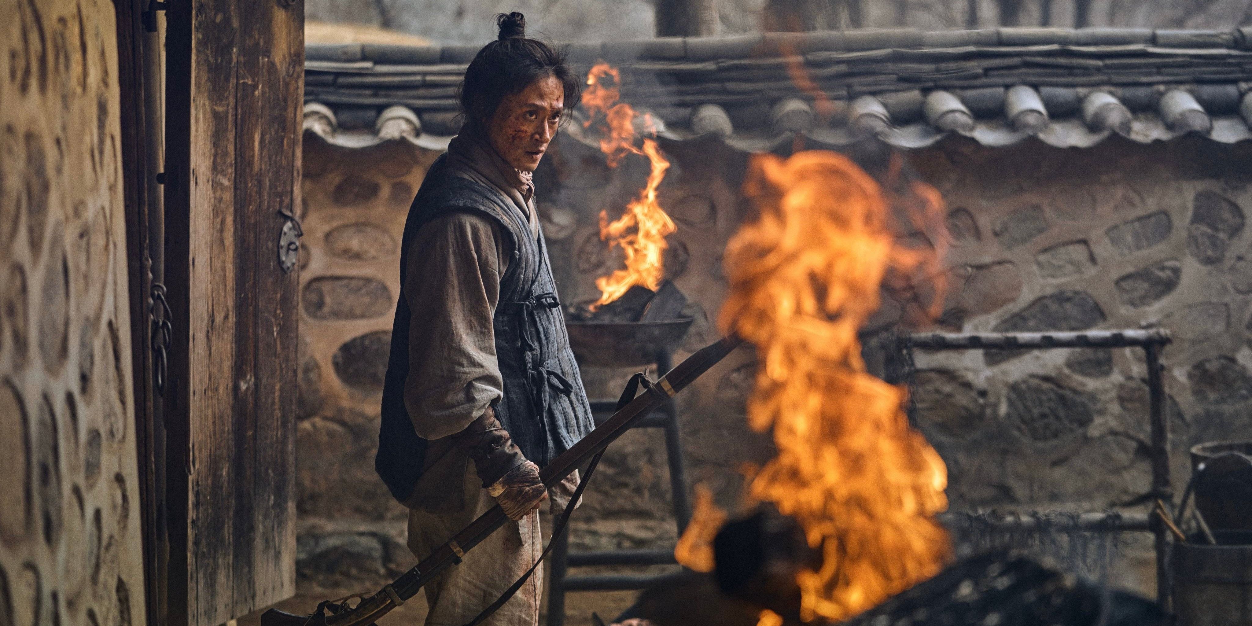 Character Yeong Shin stands within the kingdom's walls amidst the flames