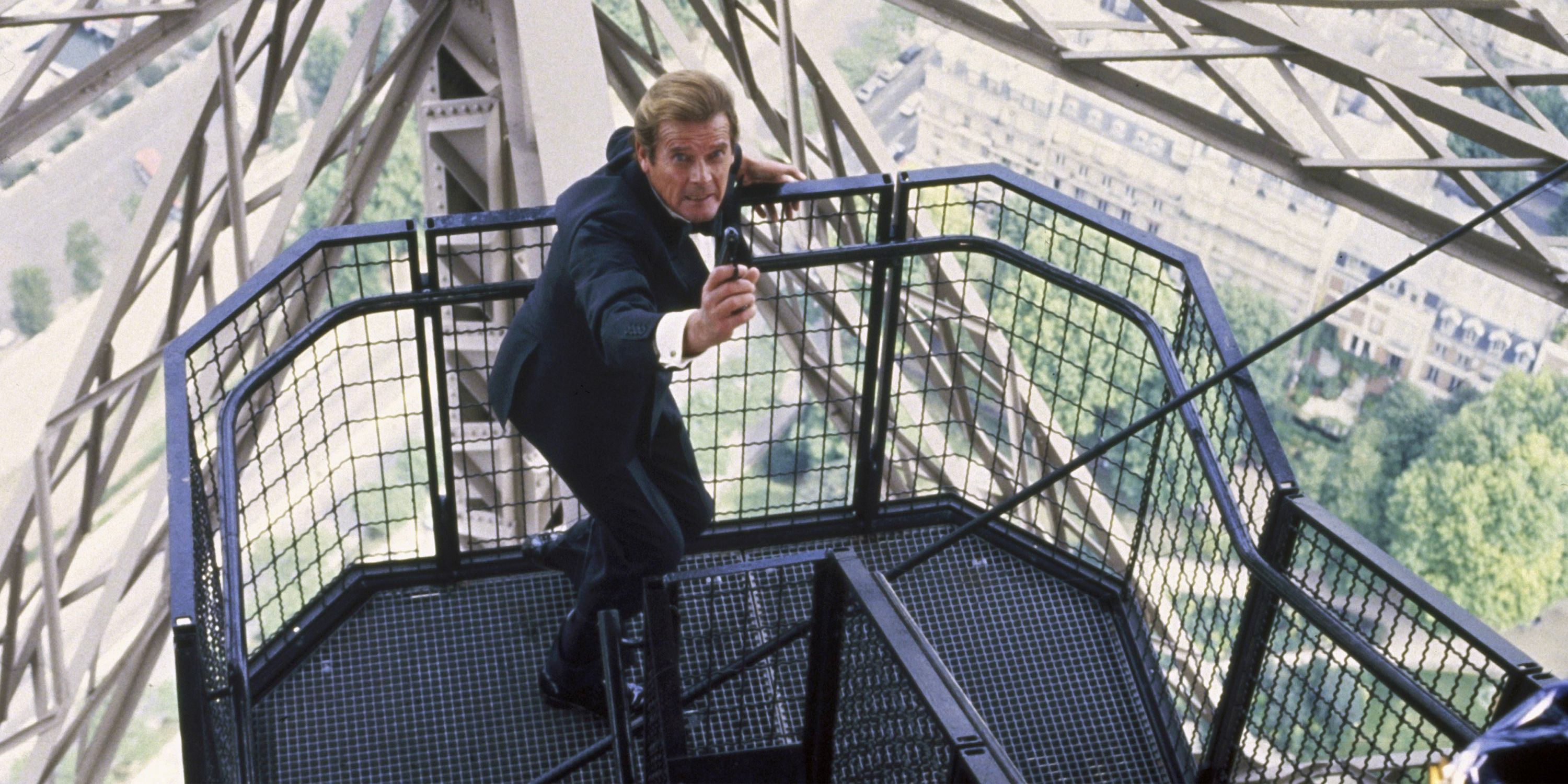 In Killing Eye, James Bond (Roger Moore) aims his weapon as he climbs a dangerously tall staircase