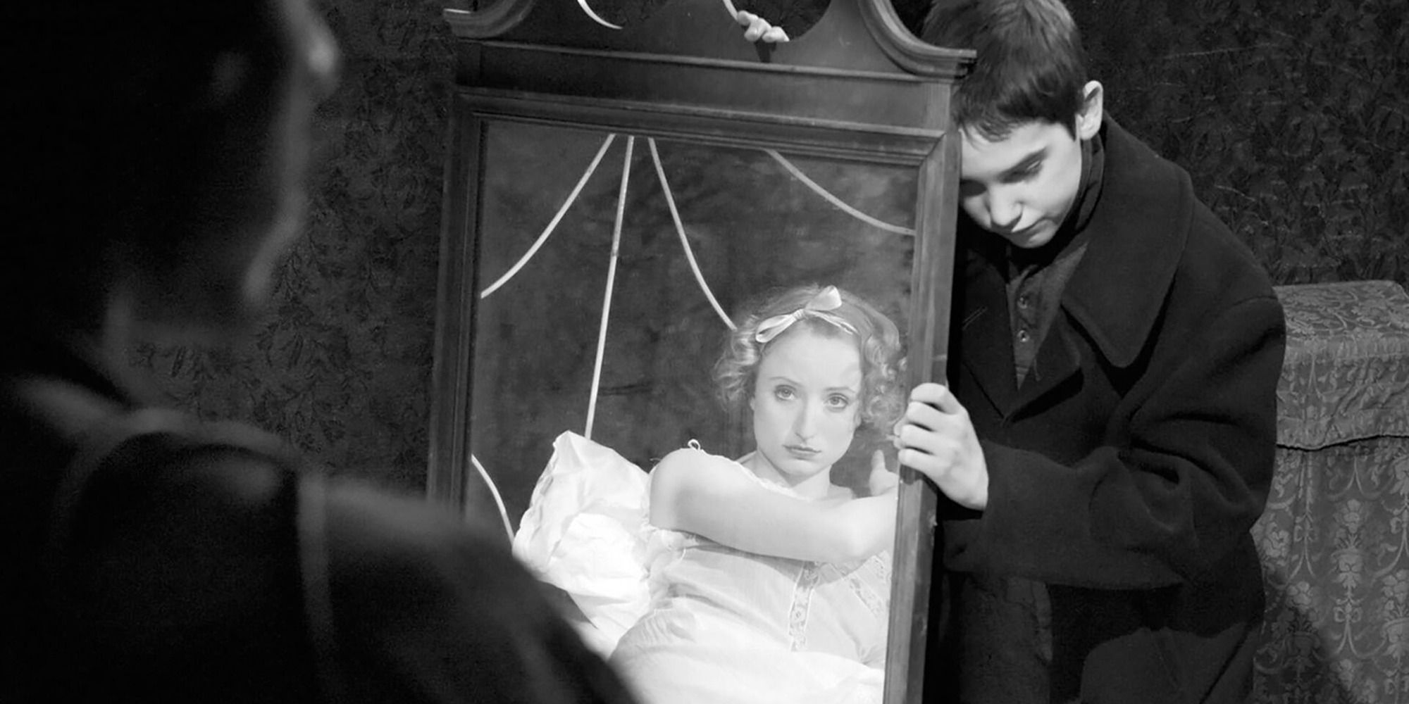 Un garçon tient un miroir devant une femme dans 