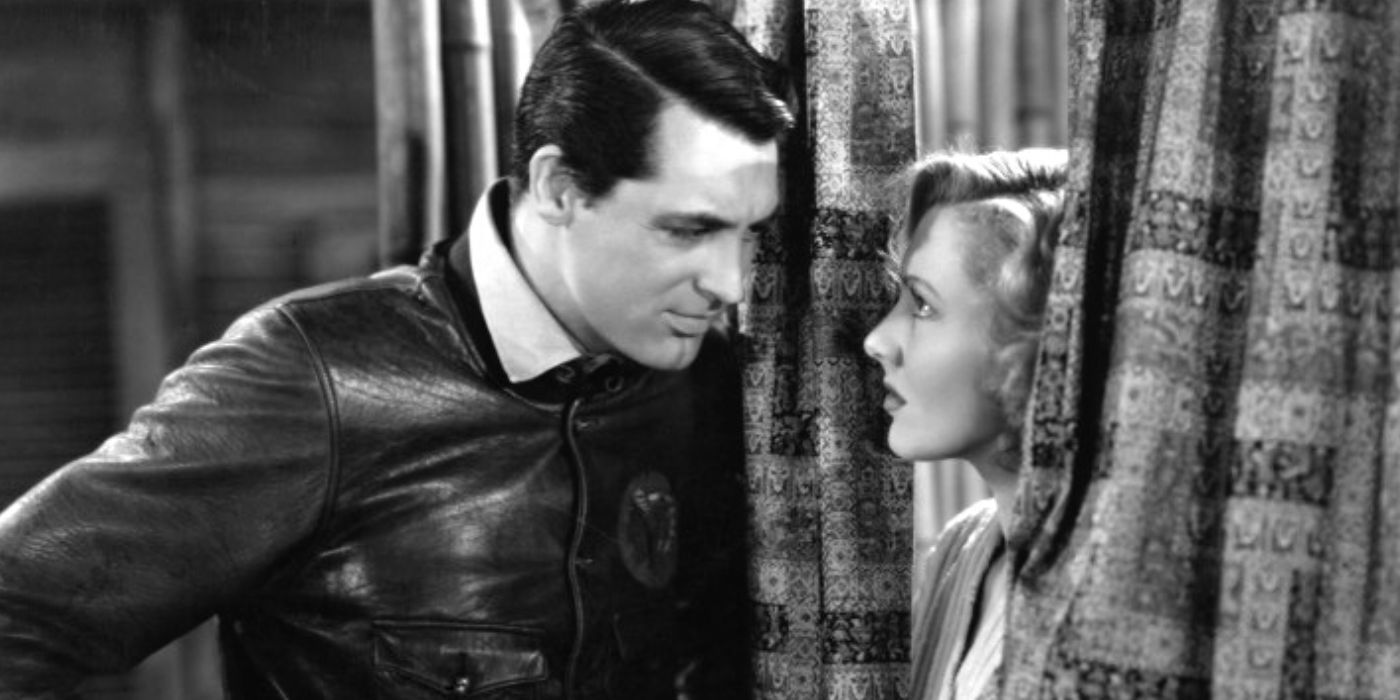 Cary Grant regarde Jean Arthur qui pointe derrière les rideaux dans Only Angels Have Wings