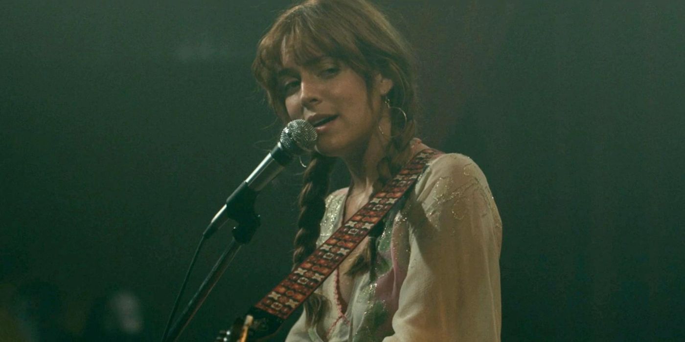 Daisy, interprétée par Riley Keough, jouant de la guitare et chantant Two Against Three dans Daisy Jones and the Six