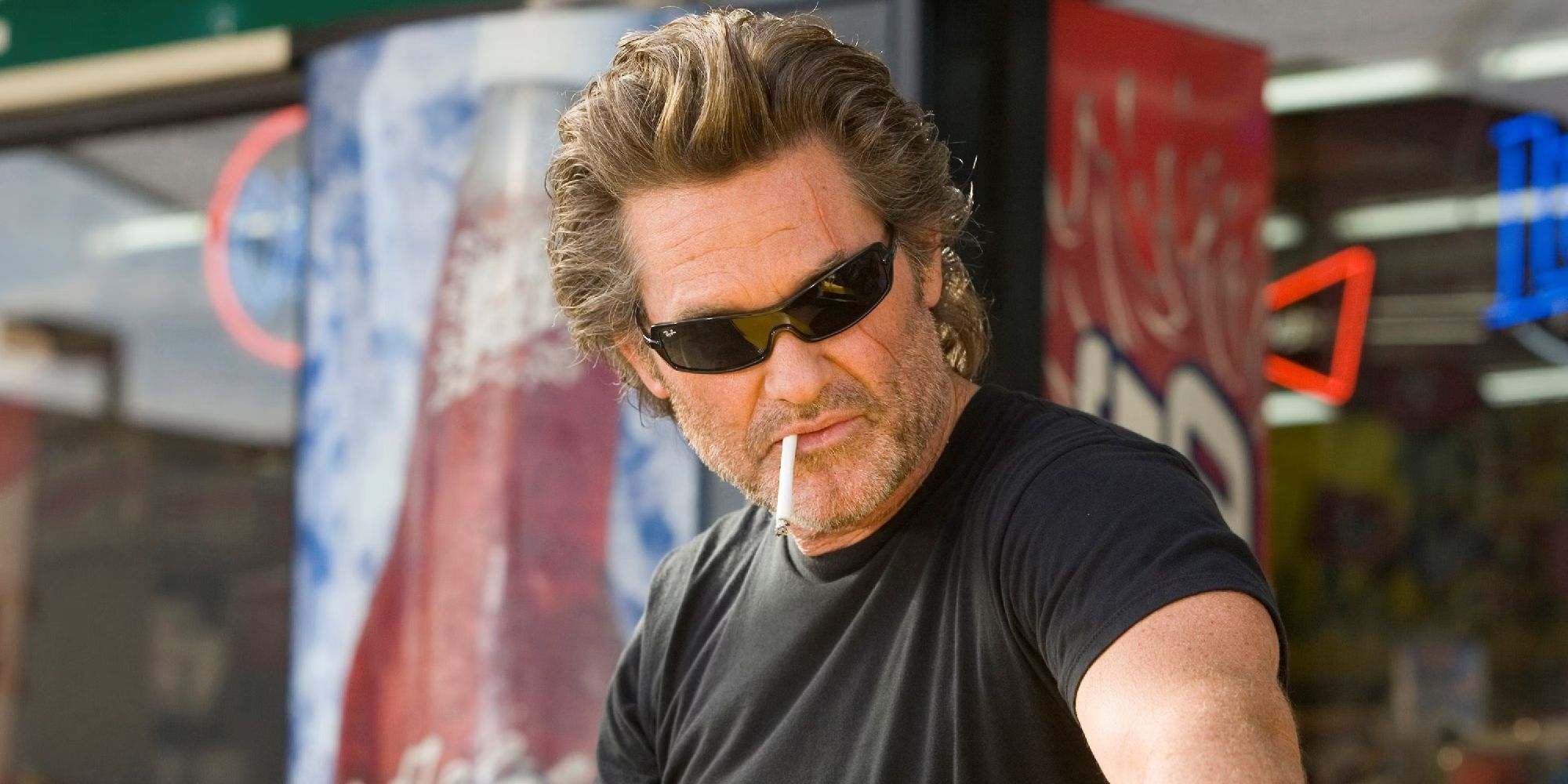 Kurt Russell, que interpreta al especialista Mike en Death Proof, lleva gafas de sol y fuma un cigarrillo.