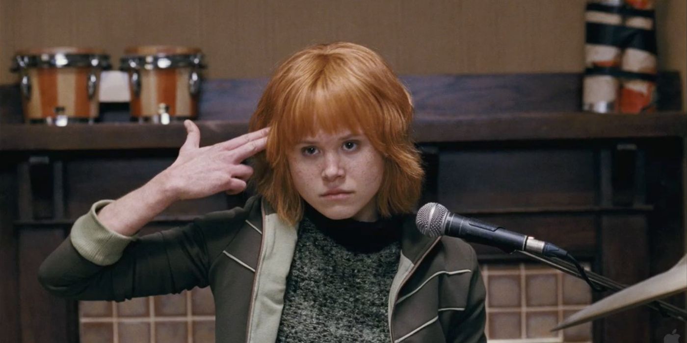 Alison Pill as Kim Pine holding her hand to her head in front of a microphone in Scott Pilgrim vs. The World
