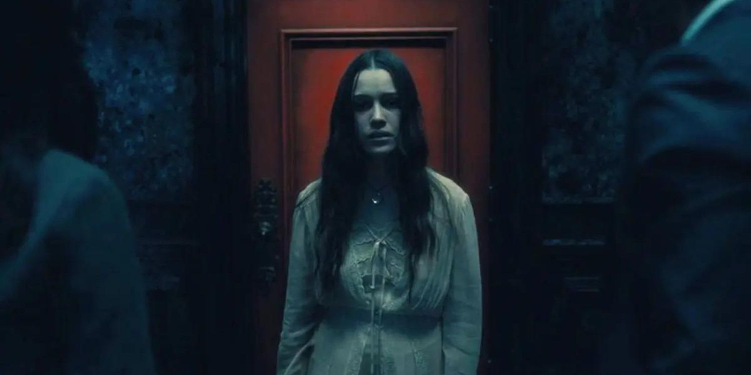 Nell devant une porte rouge, l'air triste, dans The Haunting of Hill House.