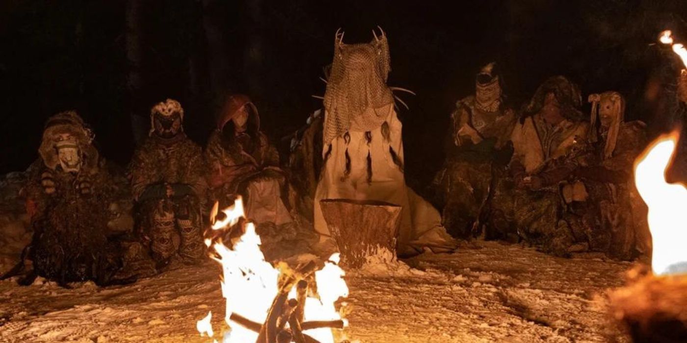 A group of masked individuals sitting in front of a fire
