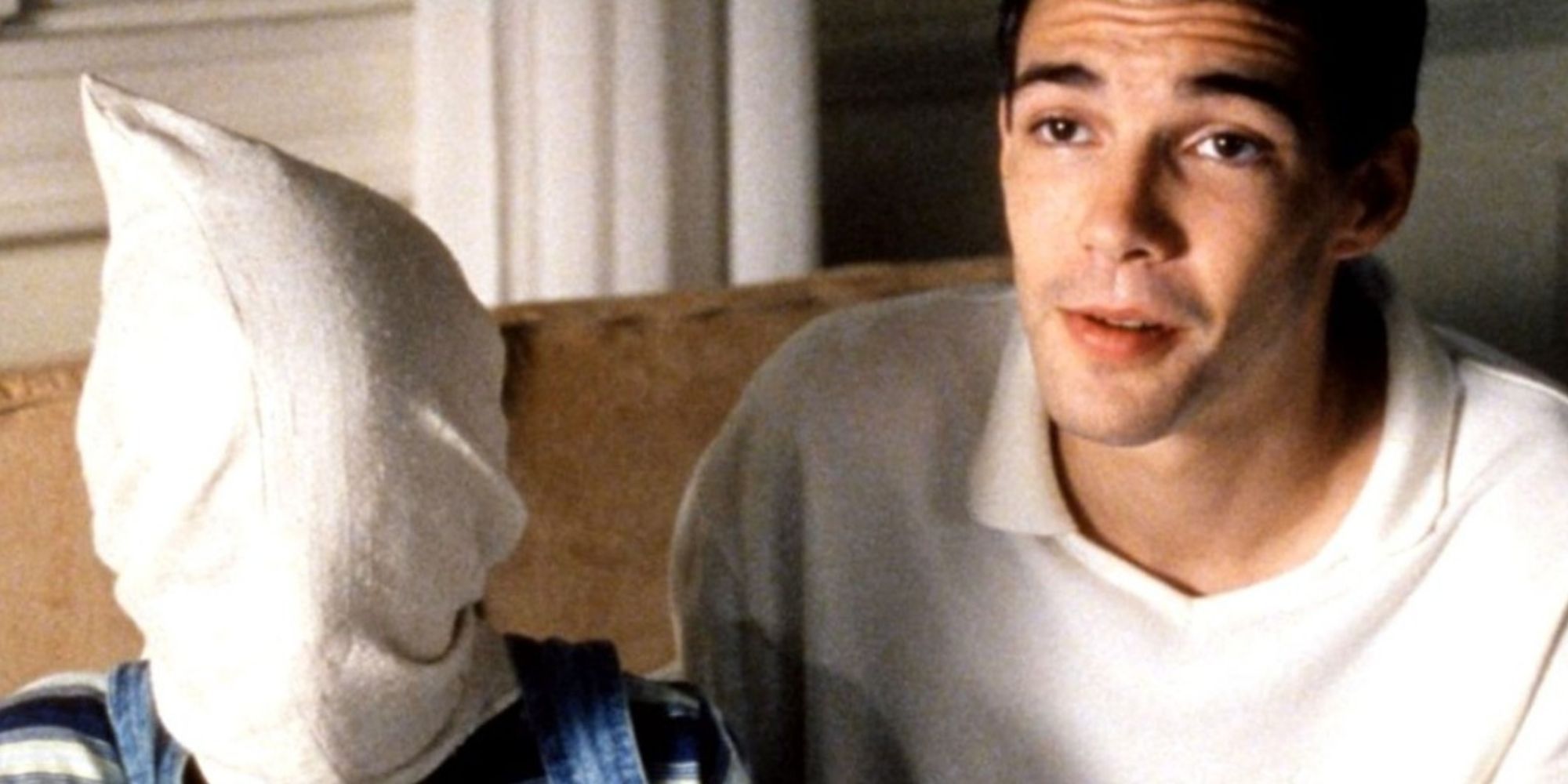 A young man beside a child whose head is covered by a pillow cover in Funny Games