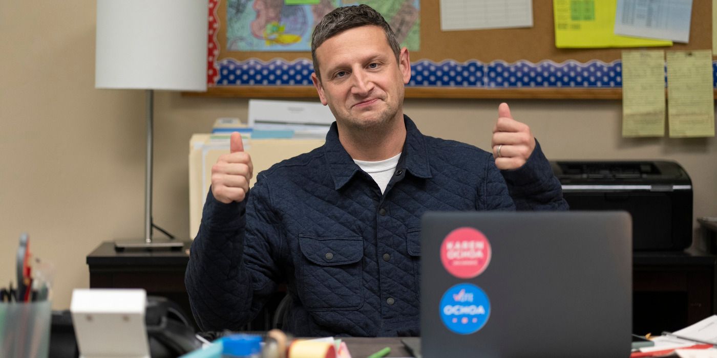 Tim Robinson looking forward with two thumbs up and sitting at a desk in I Think You Should Leave