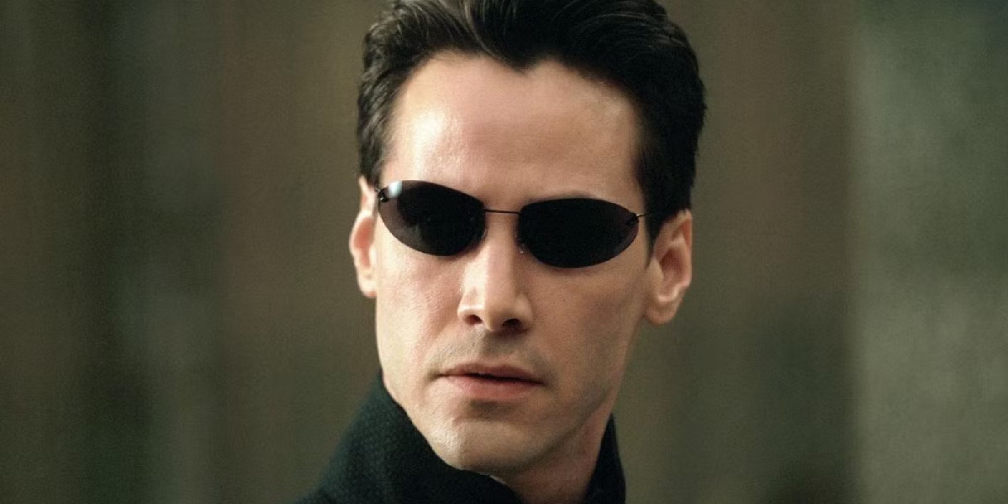 Keanu Reeves dans le rôle de Neo portant ses lunettes de soleil dans Matrix.