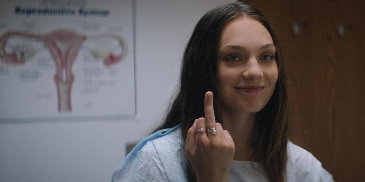 Maddie Ziegler as Lindy raising her middle finger in a doctor's office in Bloody Hell. 