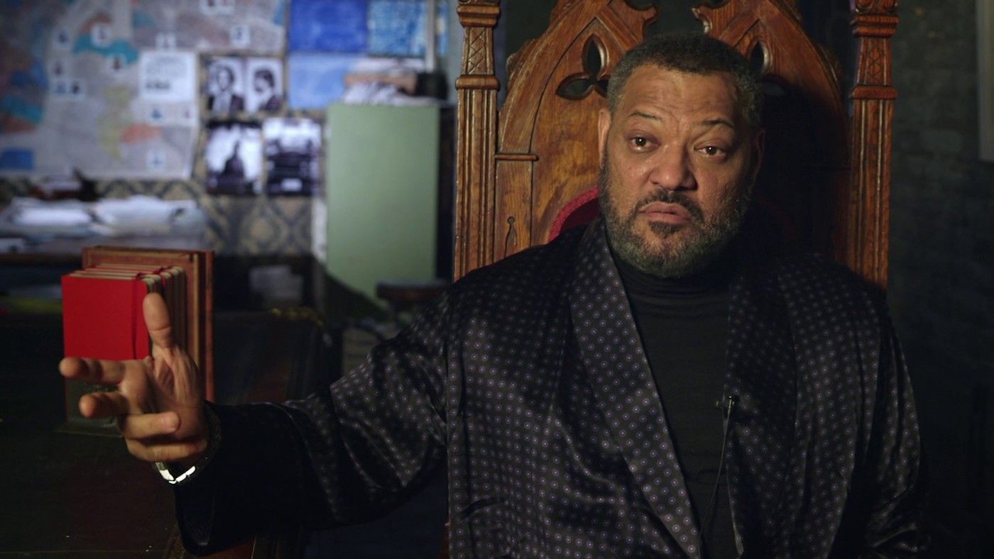 Laurence Fishburne sits in a grand wooden chair in John Wick Chapter 2