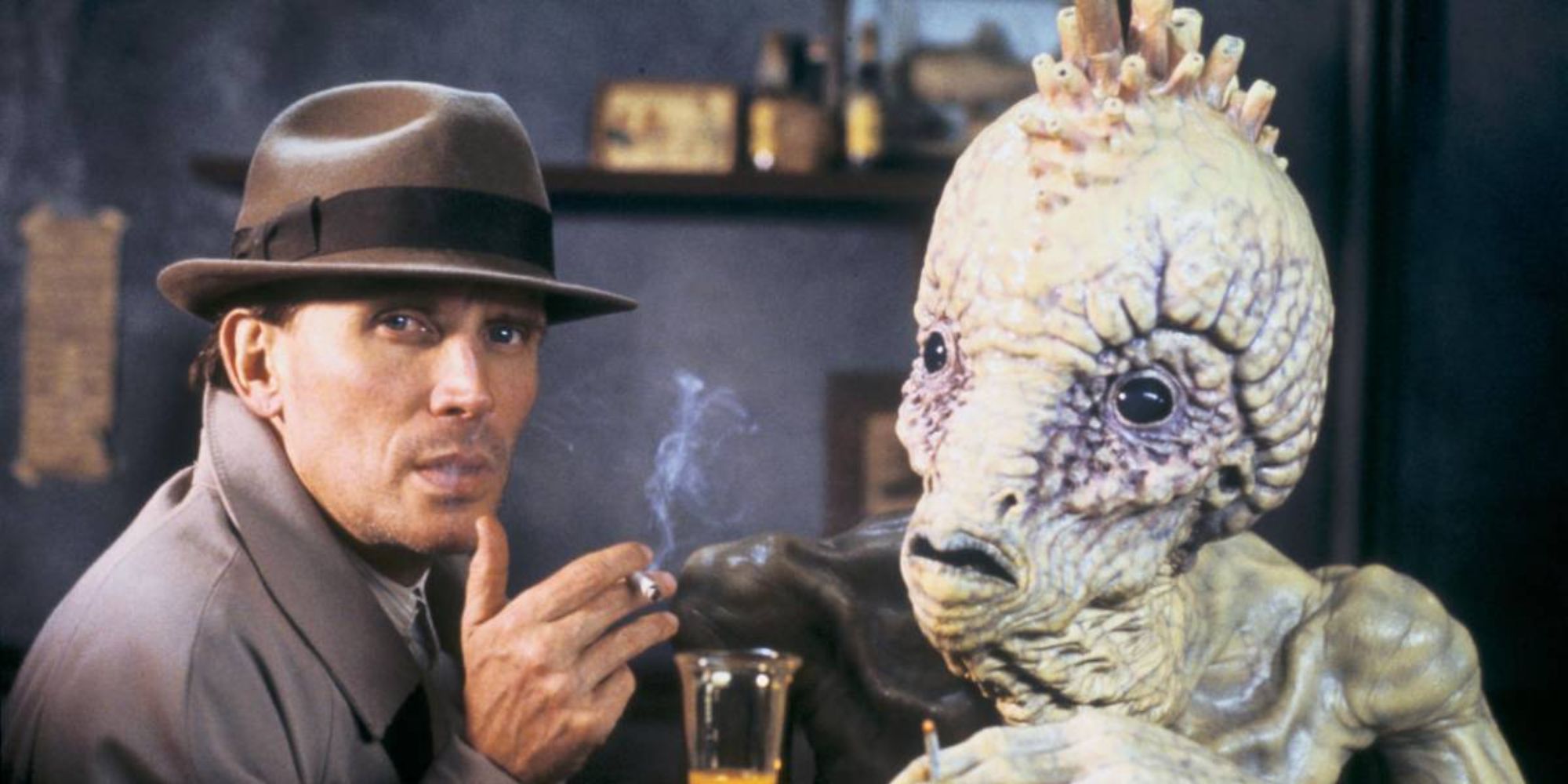 A man and a weird creature sitting next to each other and smoking in Naked Lunch’ (1991)
