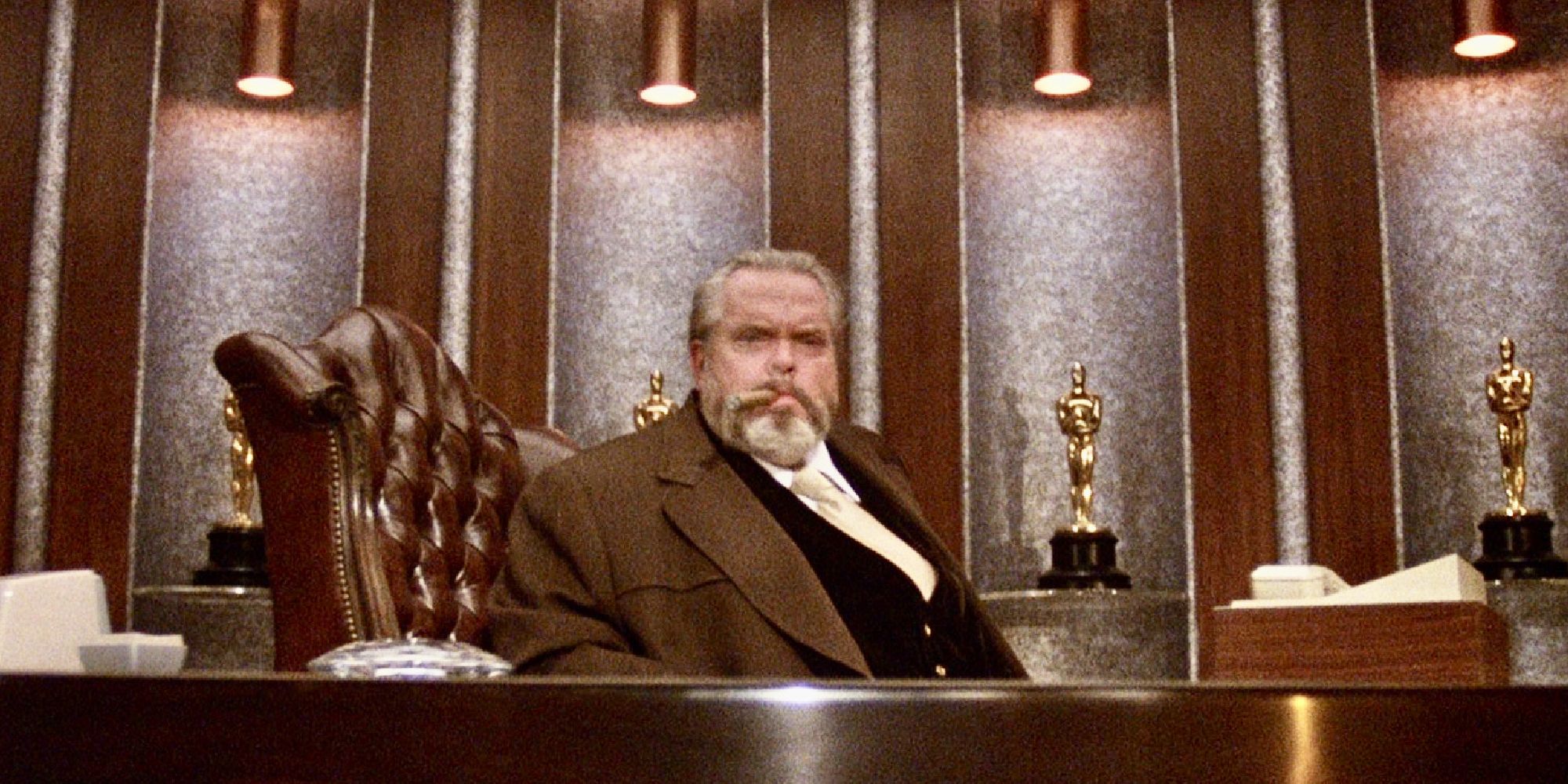 Orson Welles sitting in a chair and smoking a cigar in The Muppet Movie.
