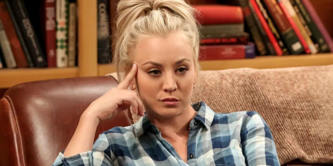 Penny, jouée par Kaley Cuoco, assise sur le canapé devant une bibliothèque, l'air ennuyé, dans The Big Bang Theory.