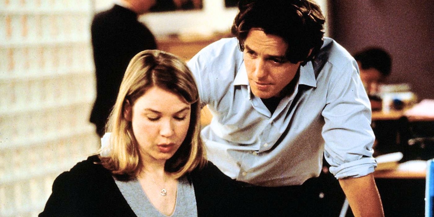 Renée Zellweger sitting at a desk while Hugh Grant is leaning over her in Bridget Jones's Diary