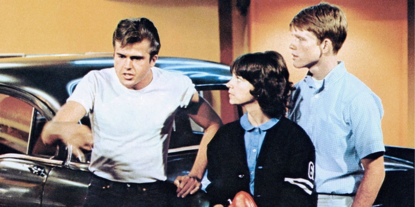 Richard Dryfuss talking while Cindy Williams and Ron Howard stand next to him in American Graffiti