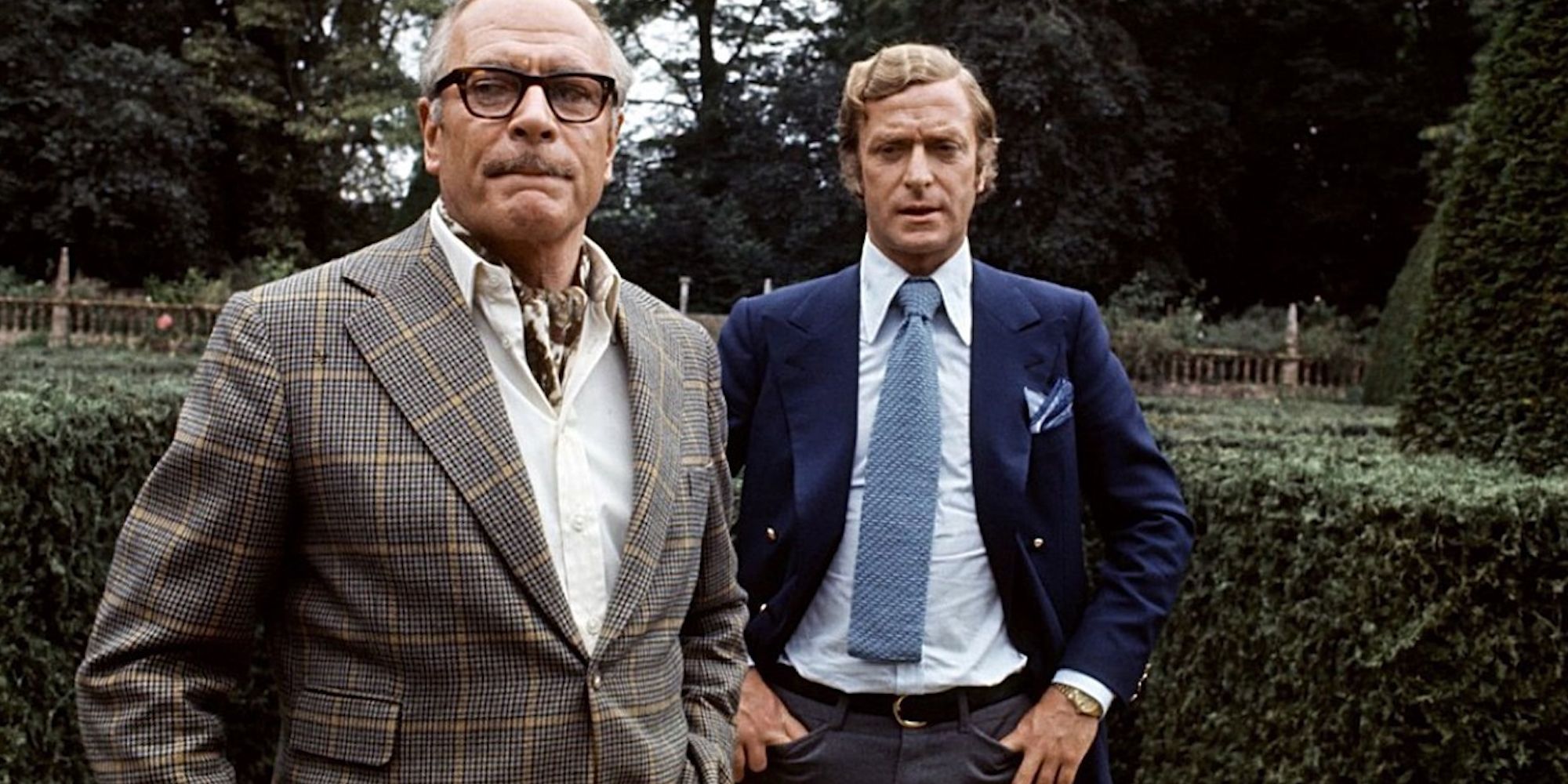 Laurence Olivier and Michael Caine standing in a garden in Sleuth (1972)