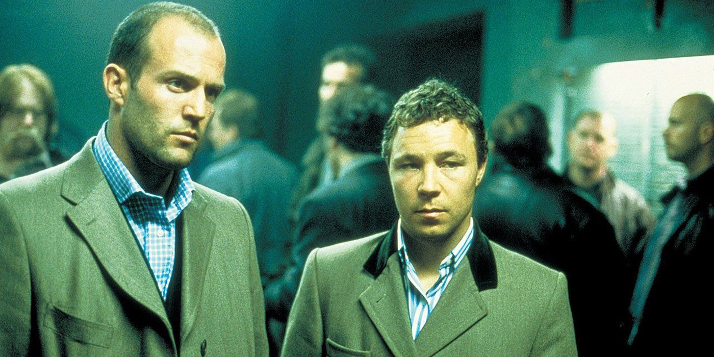 jason statham as turkish and stephen graham as tommy standing in a crowded room from snatch