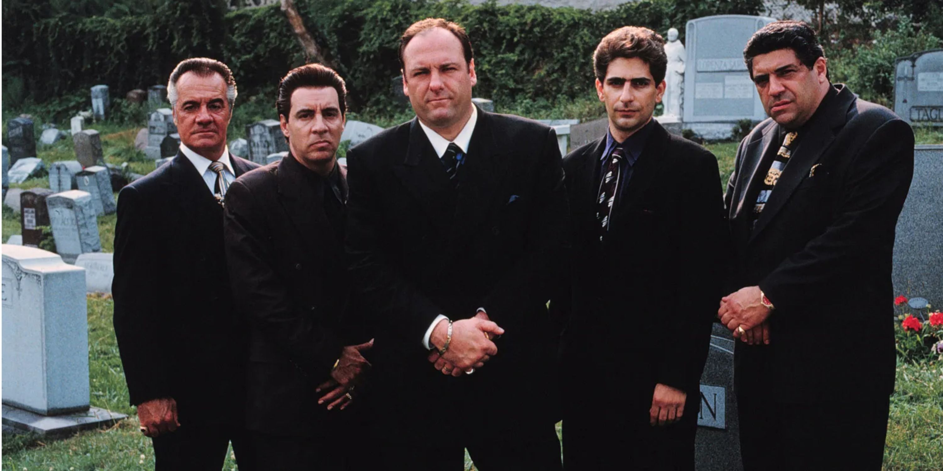 Men in suits standing in a graveyard