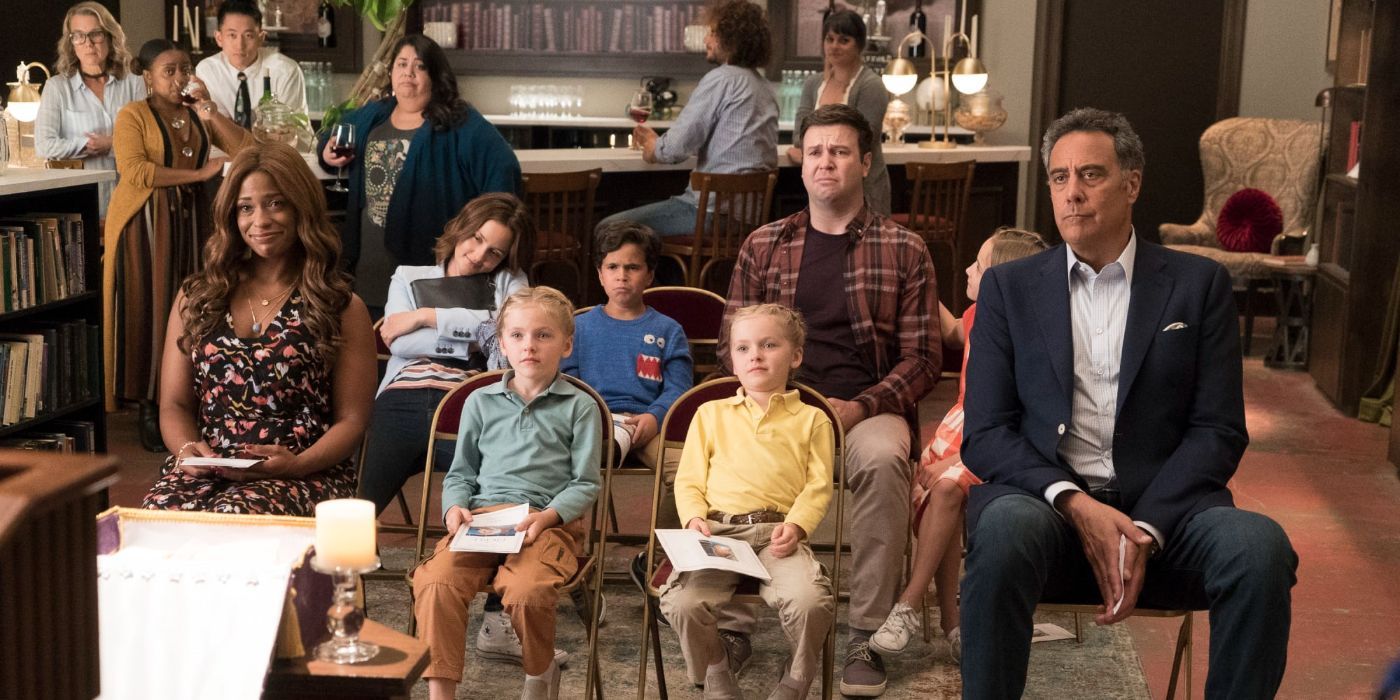 Several parents sitting in chairs in a living room with kids facing forward in Single Parents.