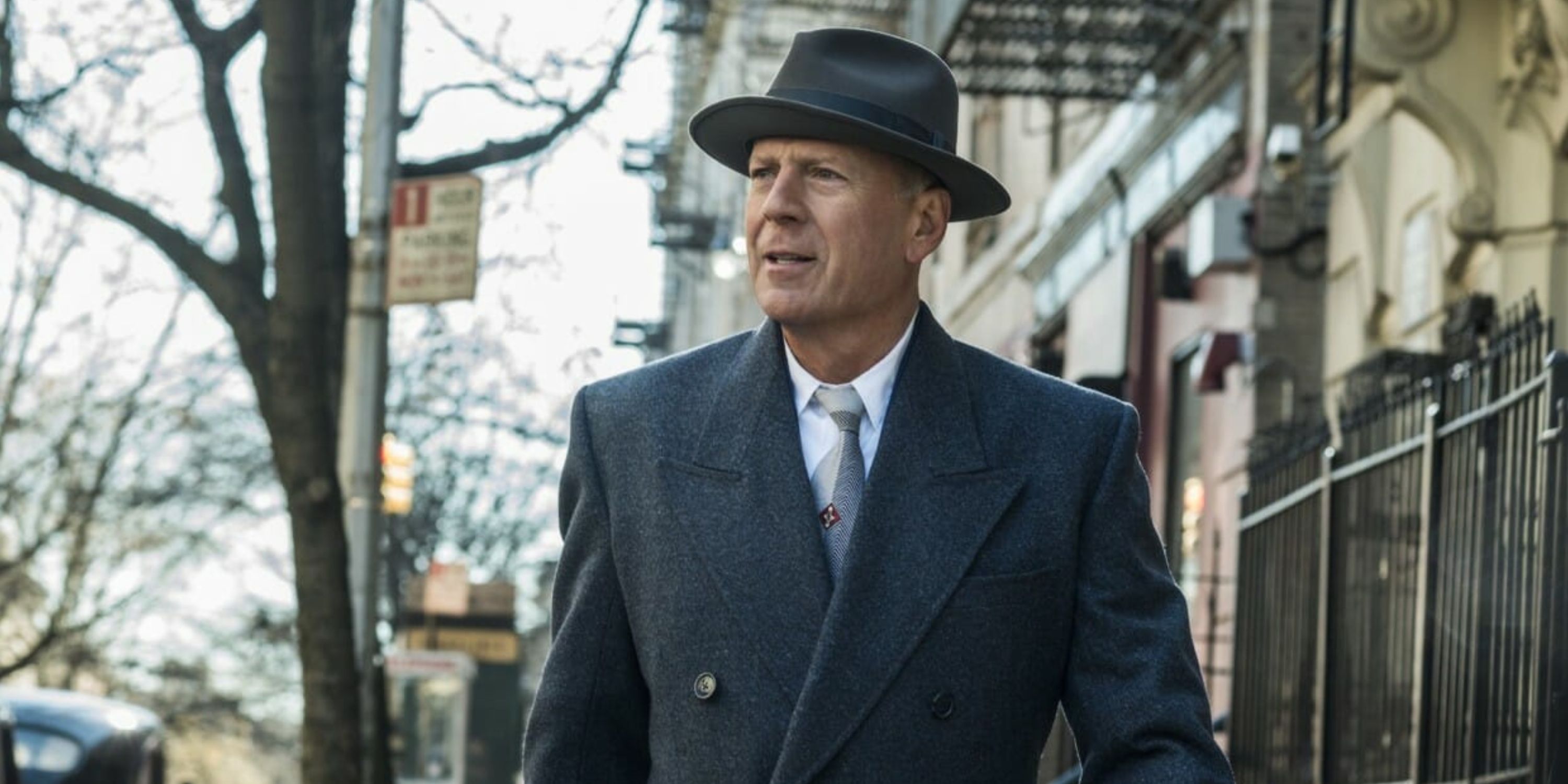 man in hat & suit standing on sidewalk