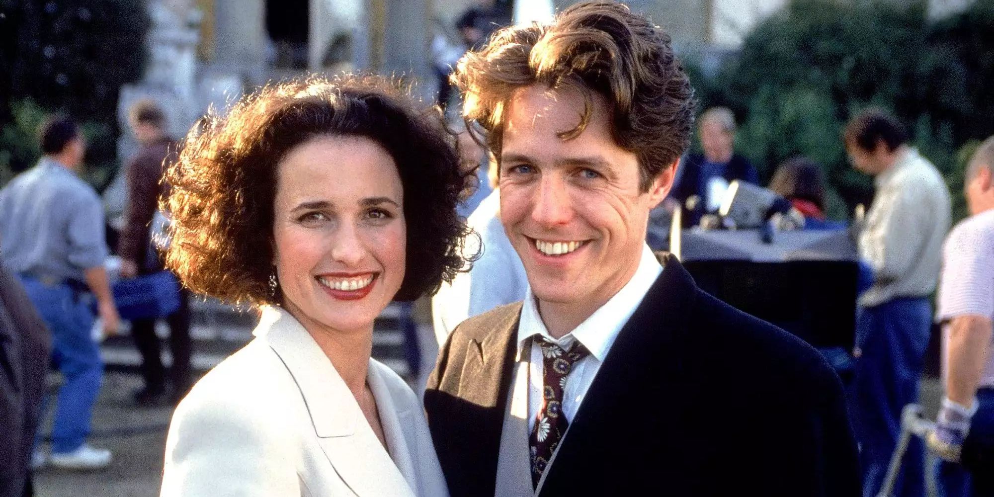 Andie MacDowell and Hugh Grant hug and smile for the camera in Four Weddings and a Funeral.