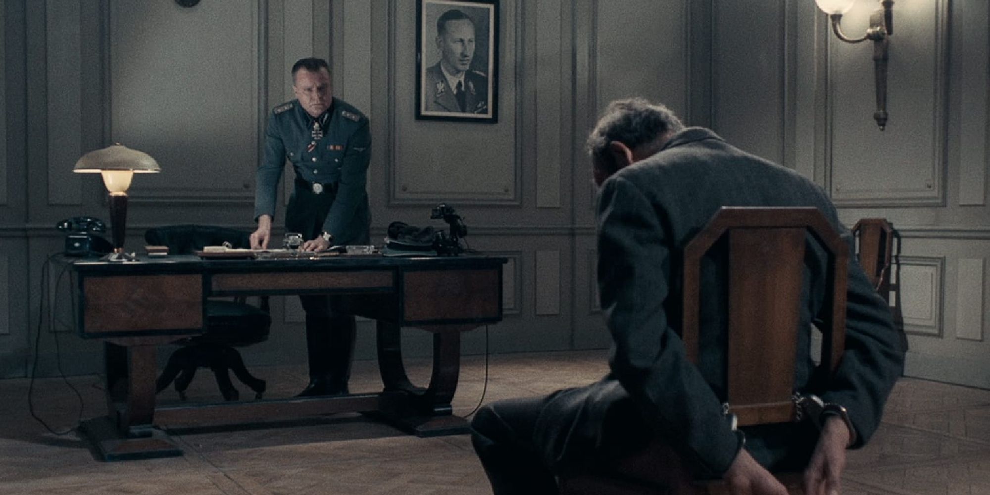 A man tied to a chair sits and a man sitting a desk in Army of Shadows 