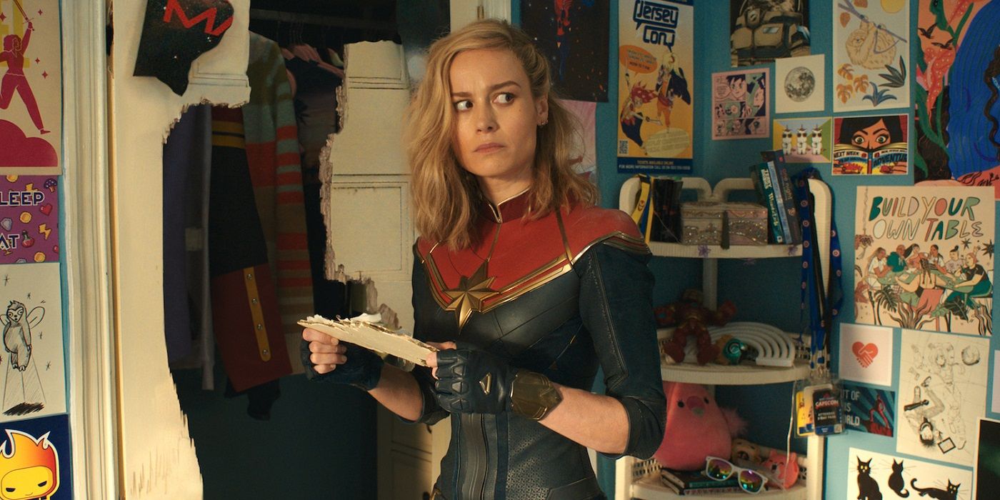 Brie Larson as Captain Marvel standing in Kamala Khan's room looking confused in The Marvels