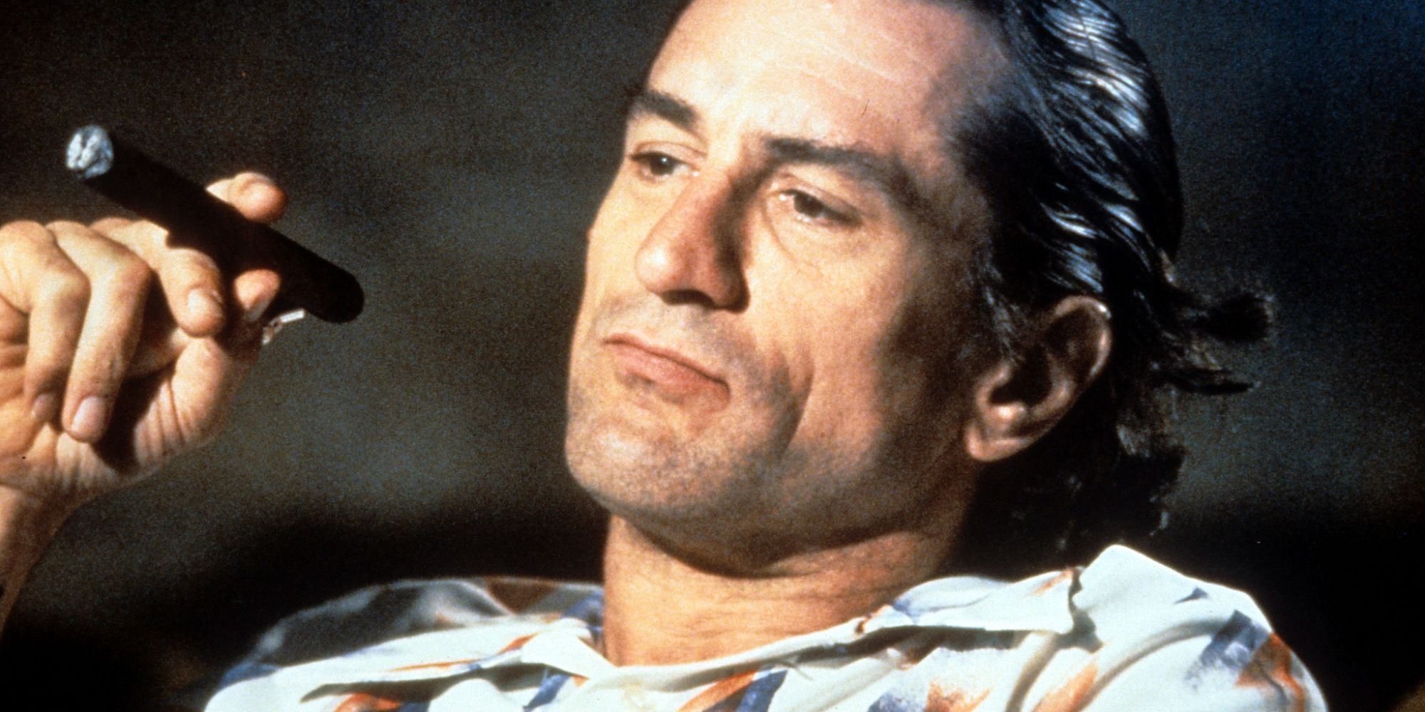 Robert De Niro as Max Caddy sitting in a theater smoking in Cape Fear