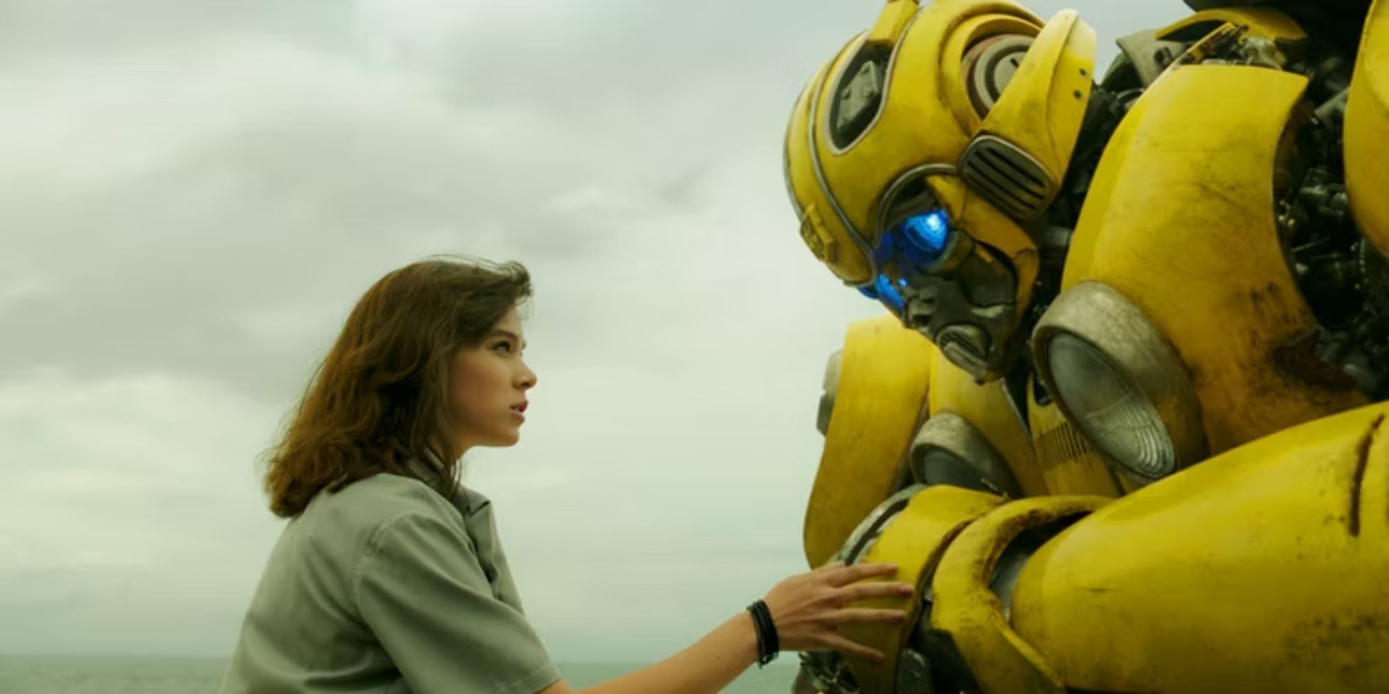 Bumblebee se agacha junto a Charlie (Hailee Steinfeld) en una escena de la película Bumblebee de 2018