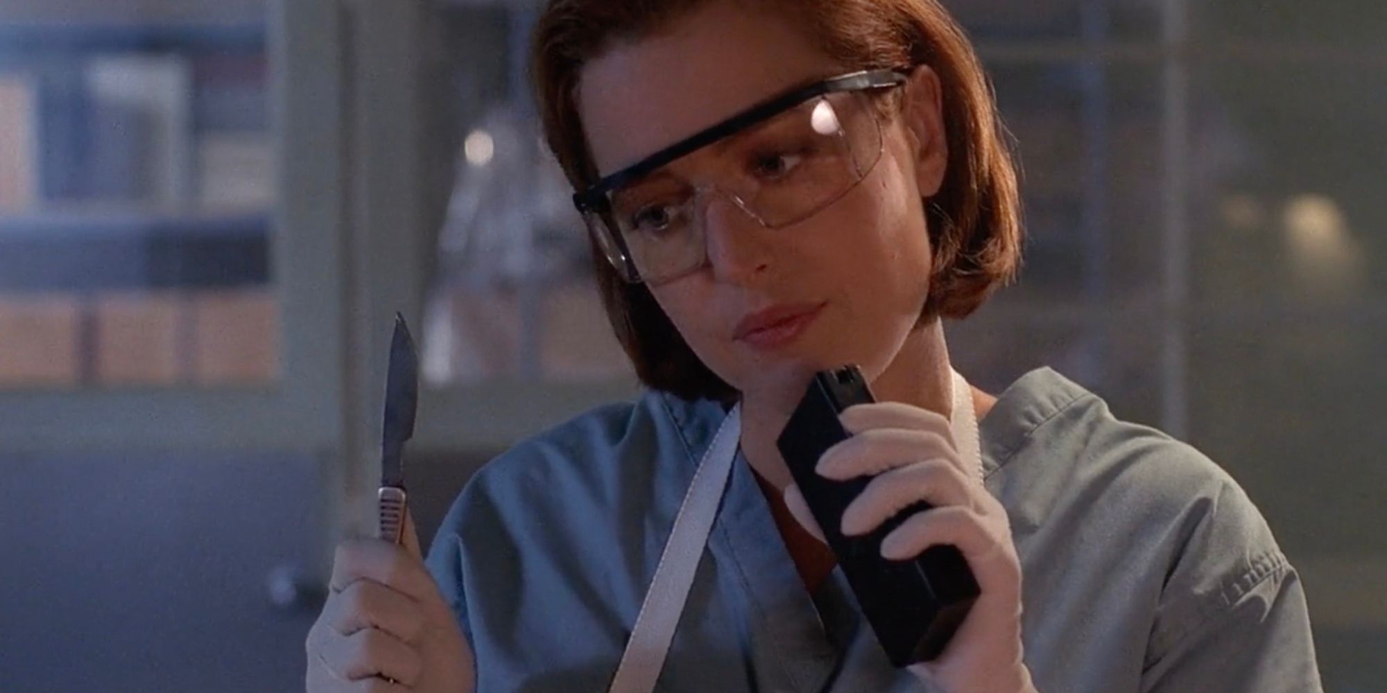 Dana Scully holds a scalpel and tape recorder in a science lab