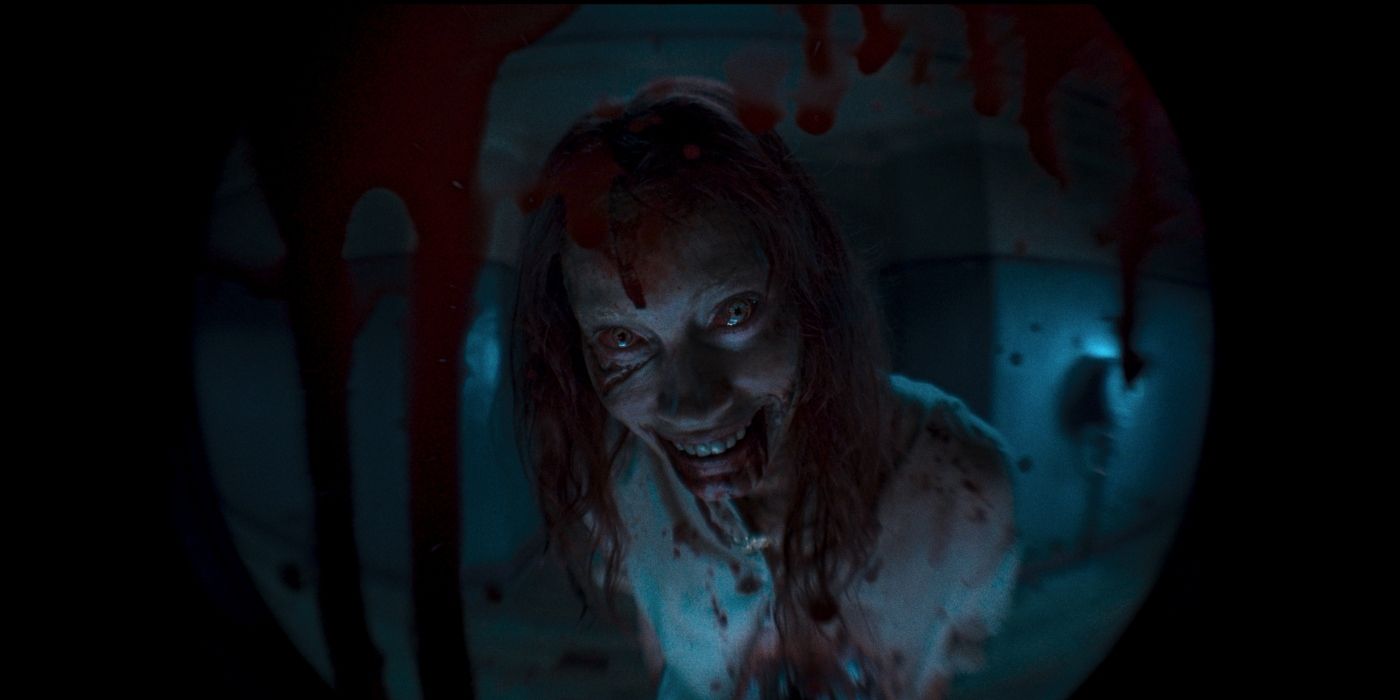 Alyssa Sutherland dans le rôle d'Ellie morte souriante à travers le judas de la porte dans Evil Dead Rise