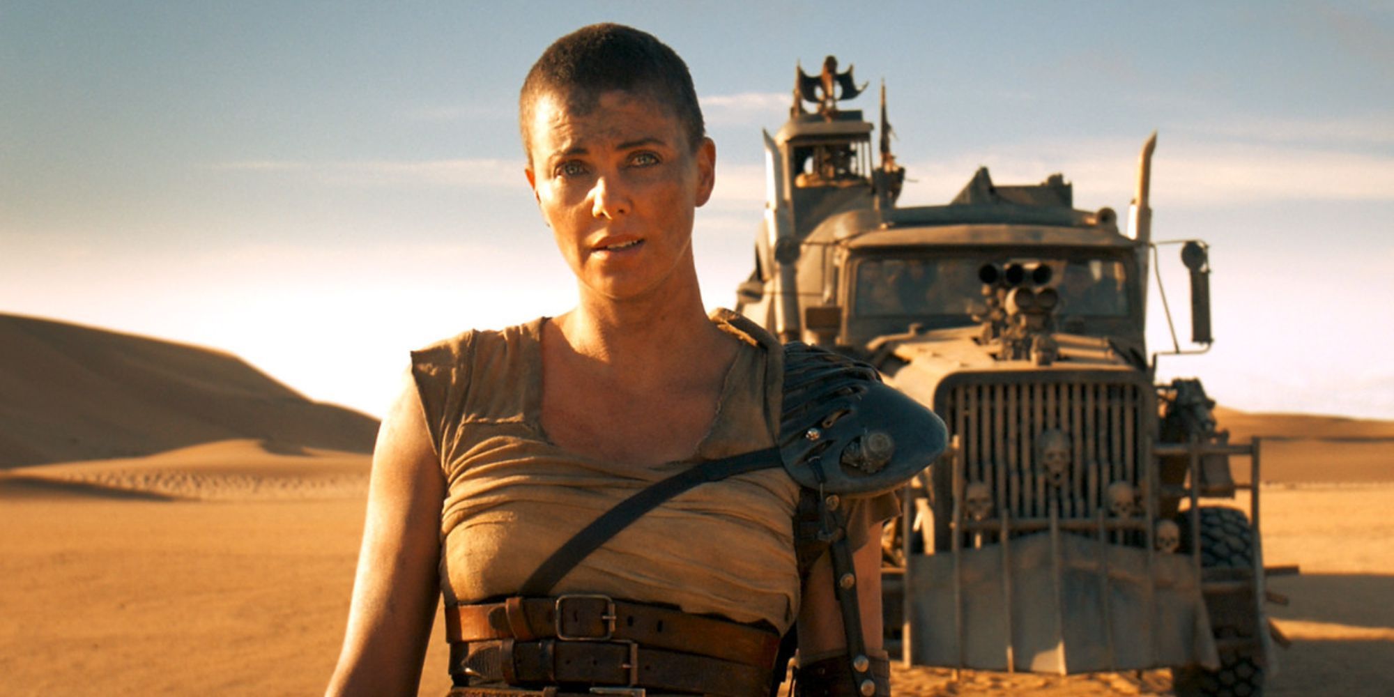 Furiosa stands in front of a truck in the desert