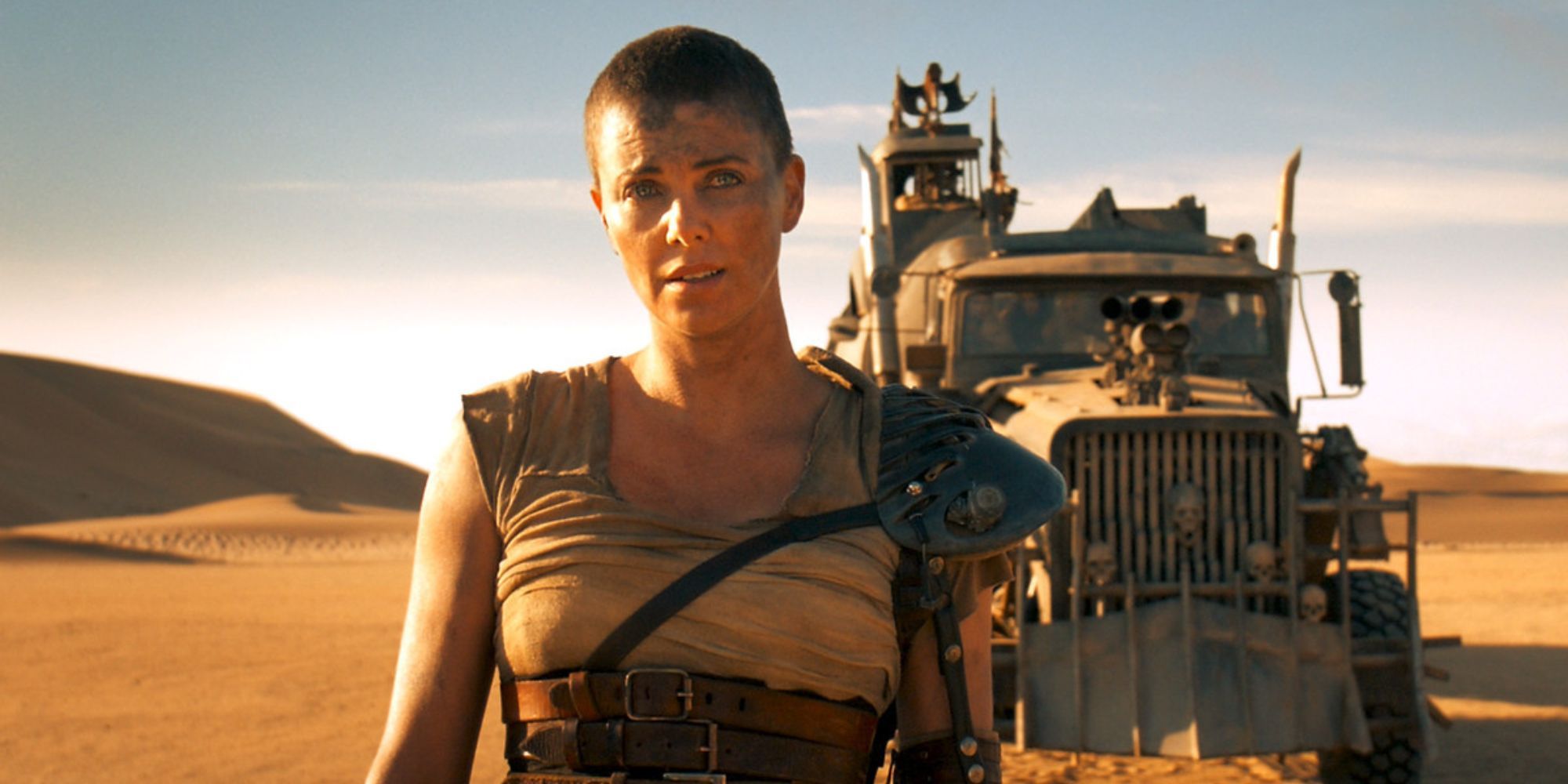 Furiosa stands in front of truck in desert in Mad Max: Fury Road.