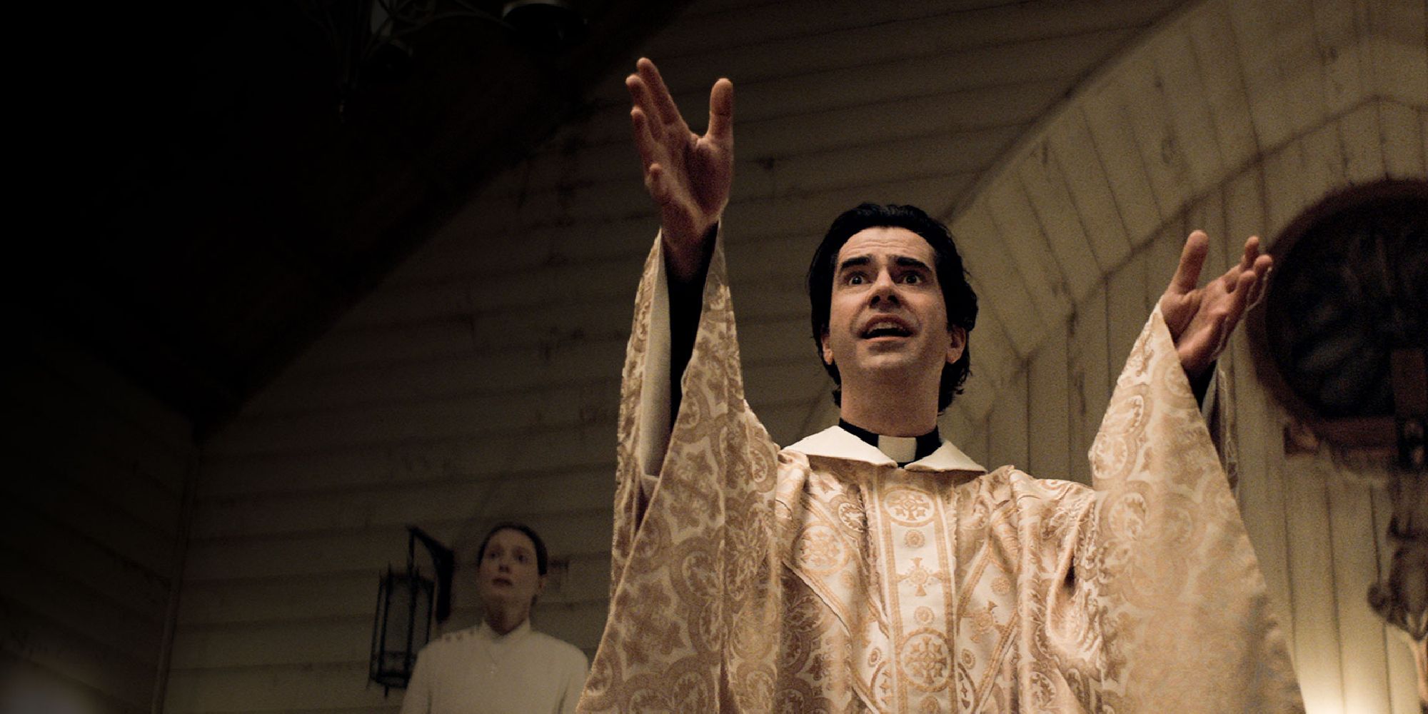 Hamish Linklater as Father Paul Hill, holding his hands outstretched with a worried expression in Midnight Mass