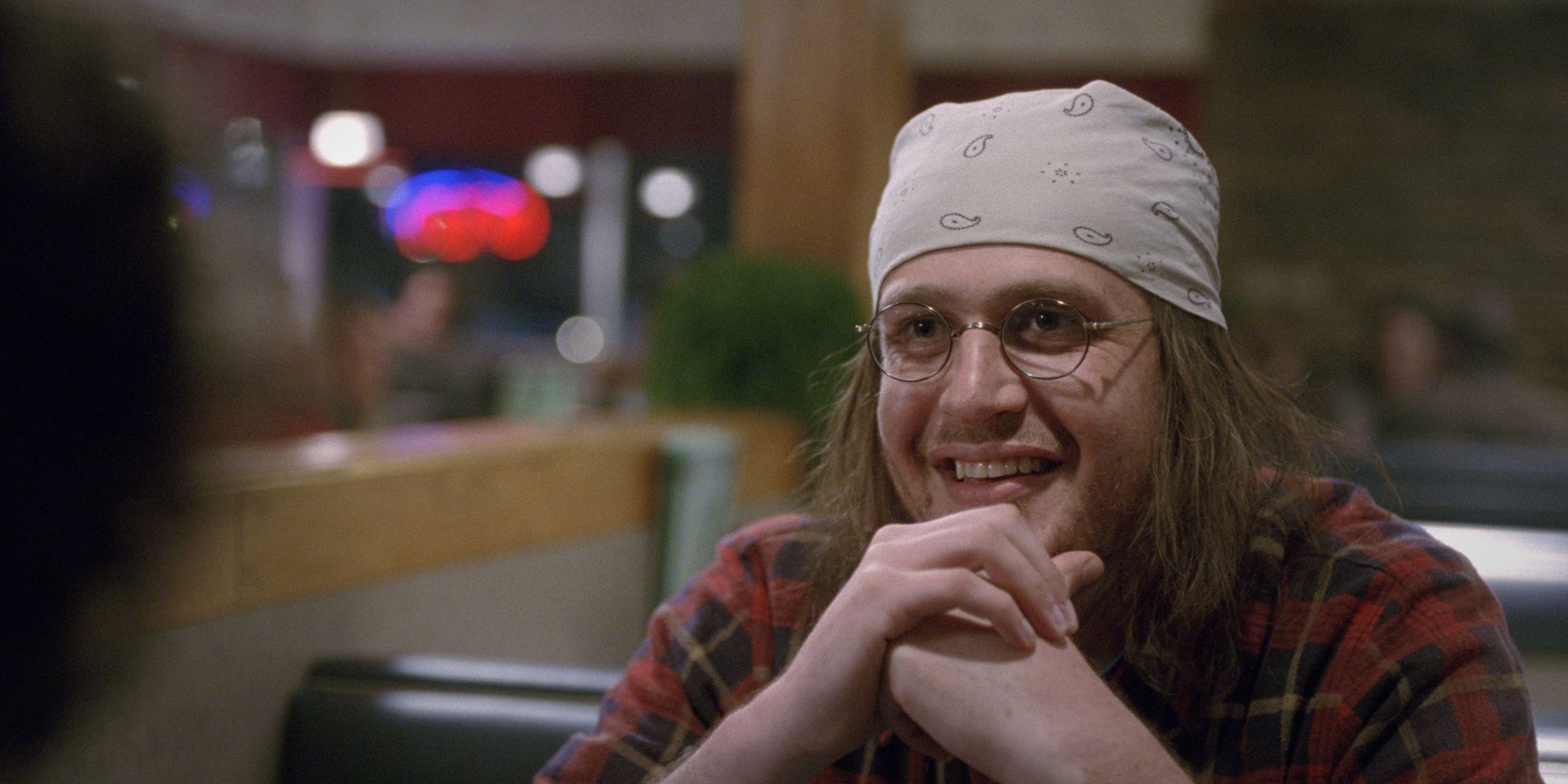 Jason Segel as David Foster smiling at someone off-camera in the film The End of the Tour