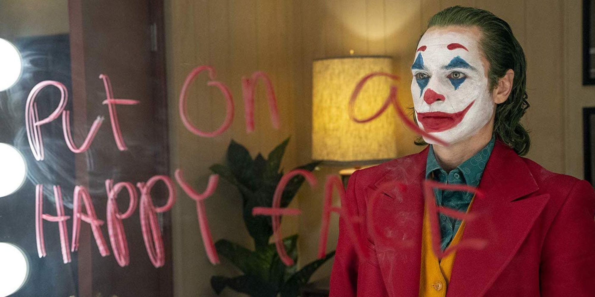 Joaquin Phoenix as the Joker stares at a mirror in Joker (2019)