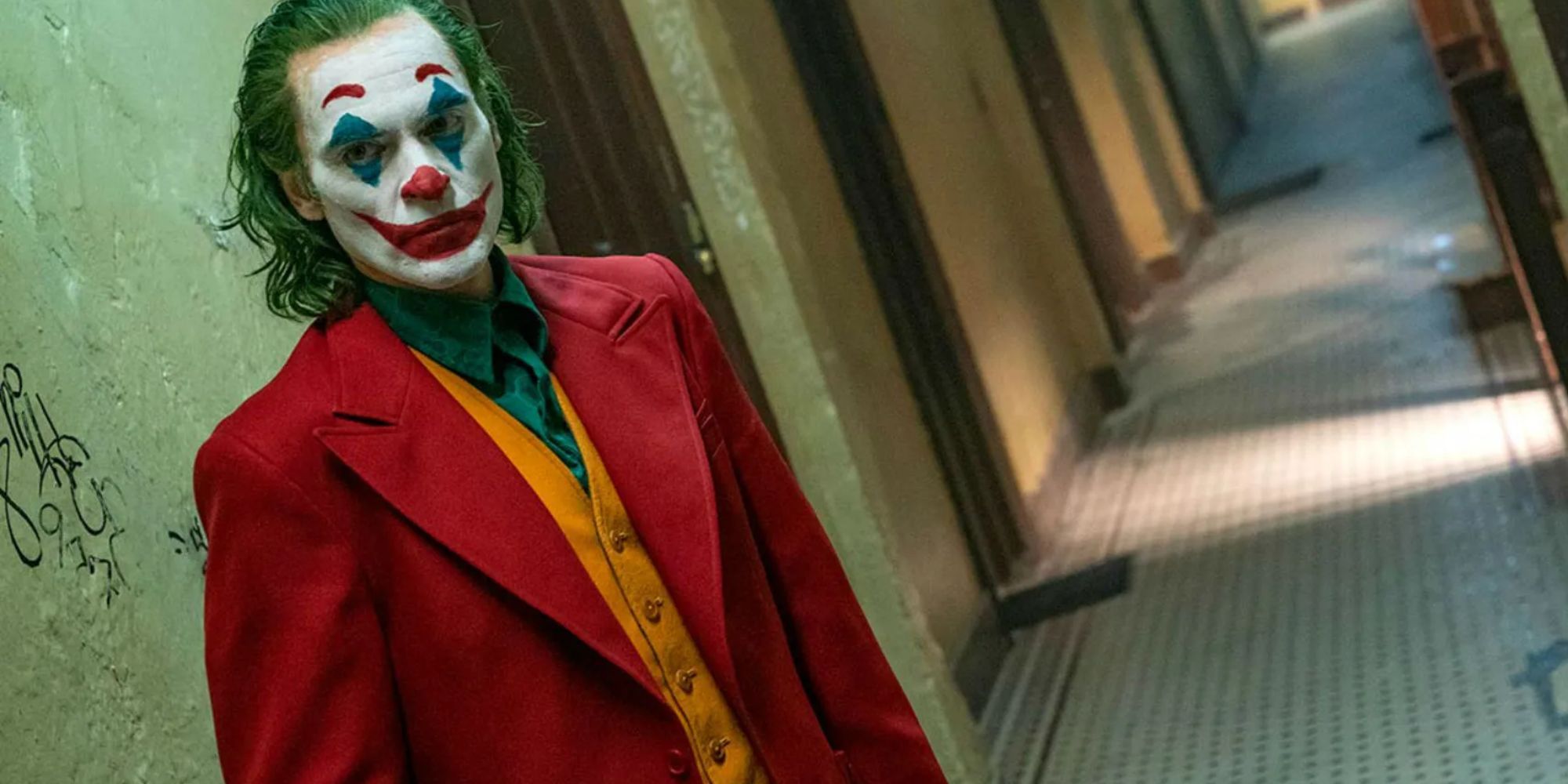 Joaquin Phoenix as the Joker standing in an empty alley in Joker.