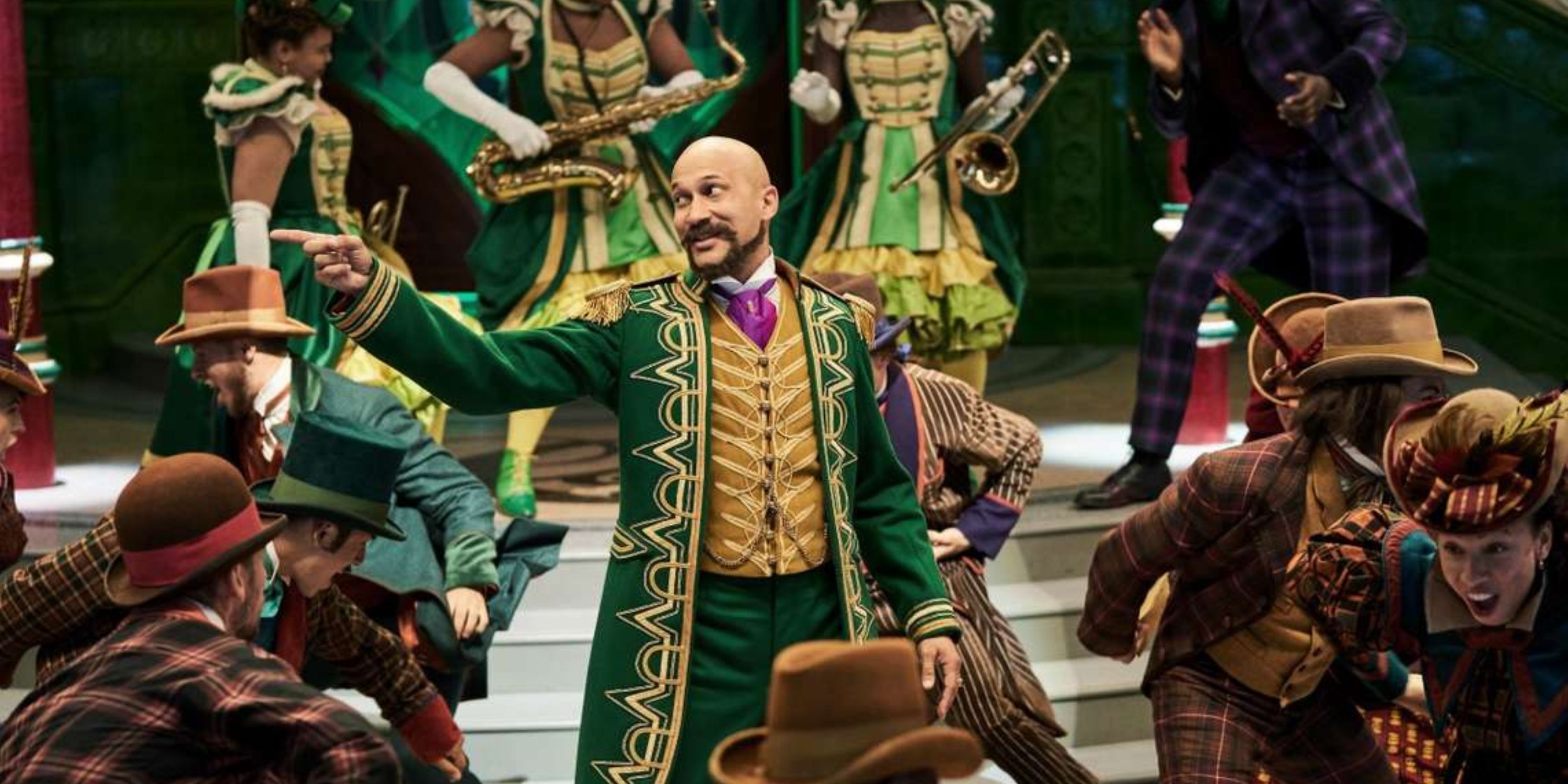 Keegan-Michael Key as Gustafson singing and pointing to his right while surrounded by dancers in Jingle Jangle: A Christmas Journey