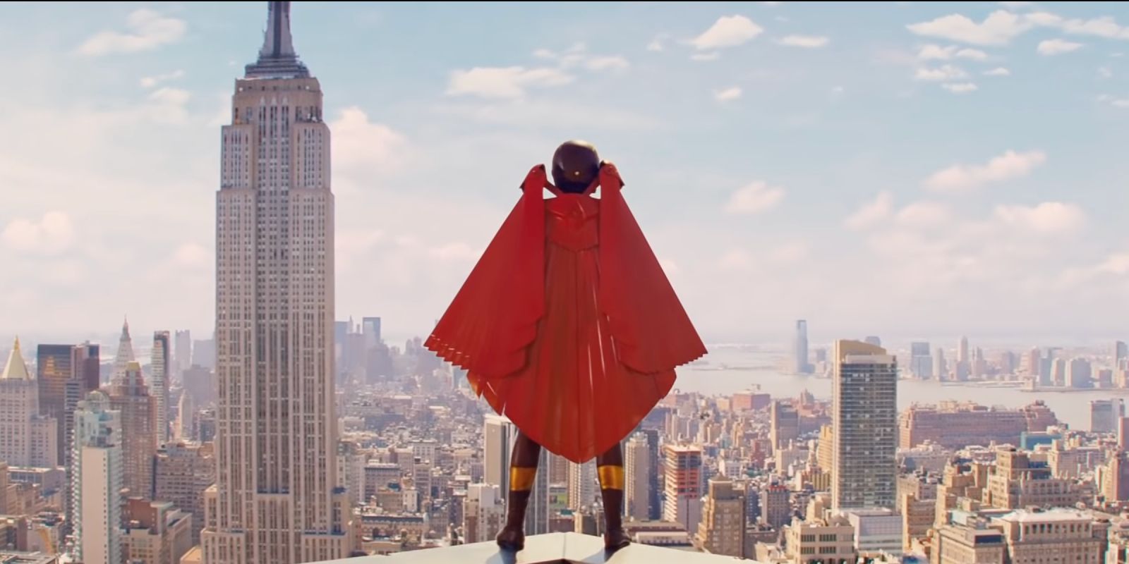 A costumed superhero stands atop a building looking over New York City. 