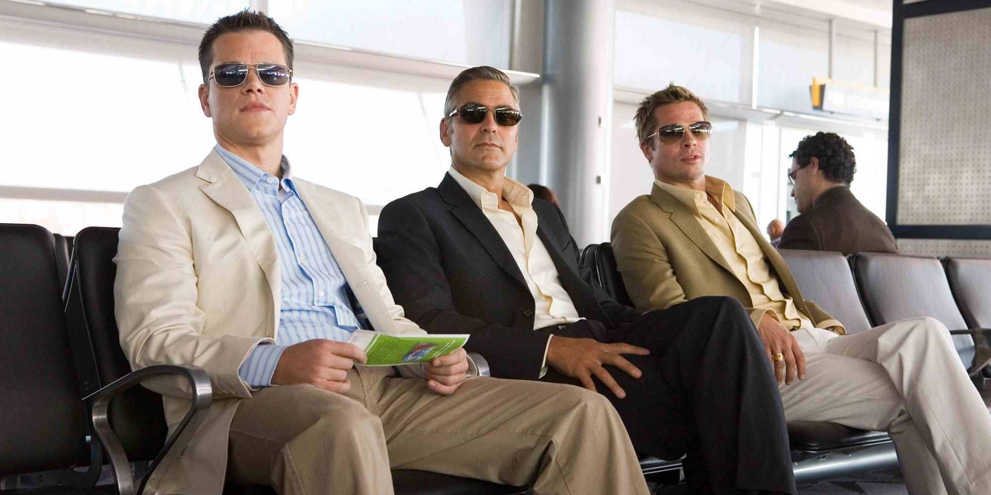 Matt Damon, George Clooney and Brad Pitt in 'Ocean's Thirteen' sitting at an airport with sunglasses on