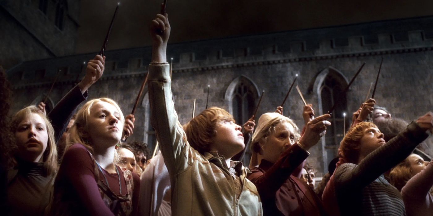 The students and staff of Hogwarts raise their wands in honor of Dumbledore in Harry Potter and the Half-Blood Prince